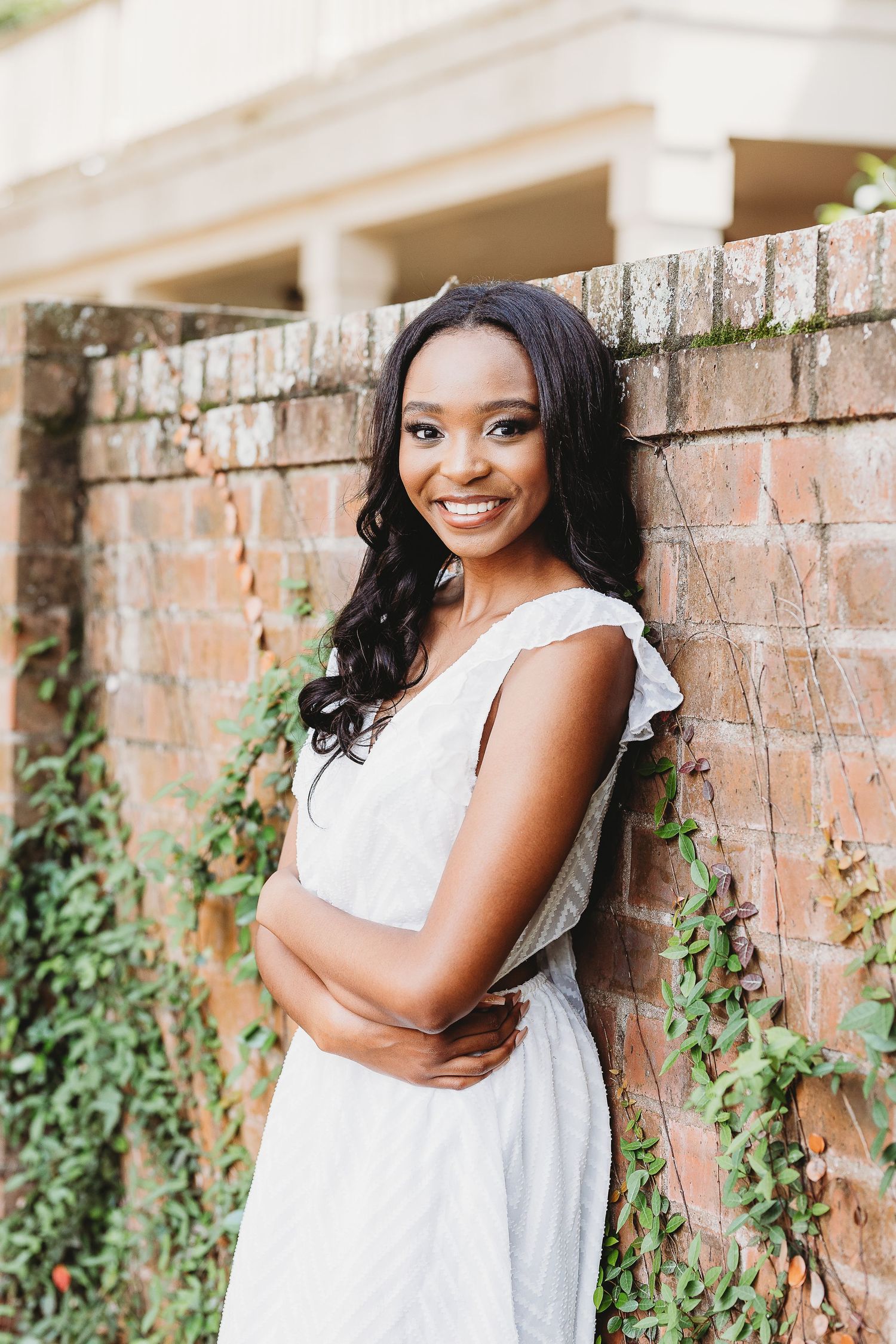 Elegant portraits against a brick wall with white dress and climbing ivy backdrop.
