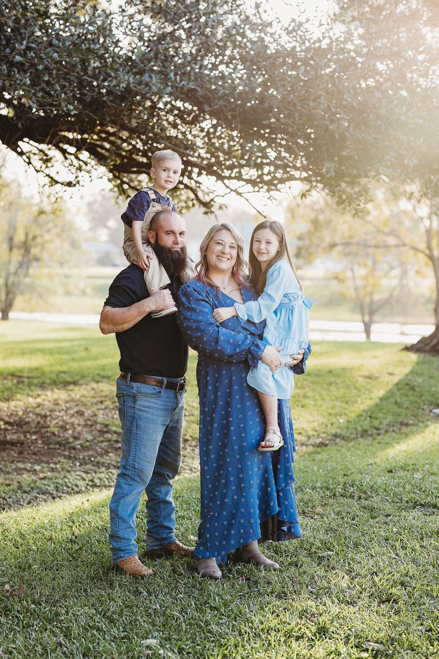 A family stands together outdoors wearing coordinating blue and black outfits.