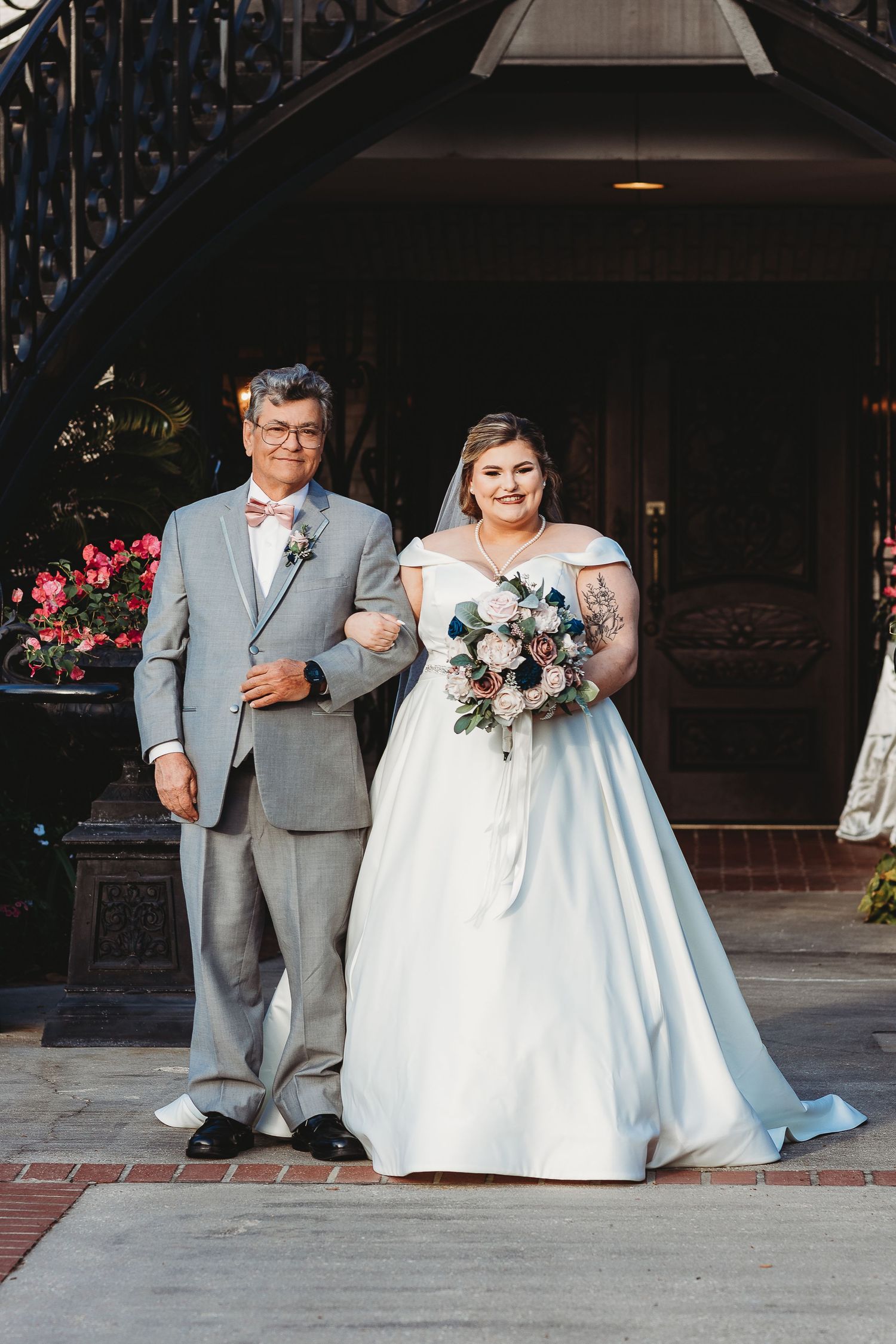 A wedding couple sits together on outdoor stone steps in formal attire.