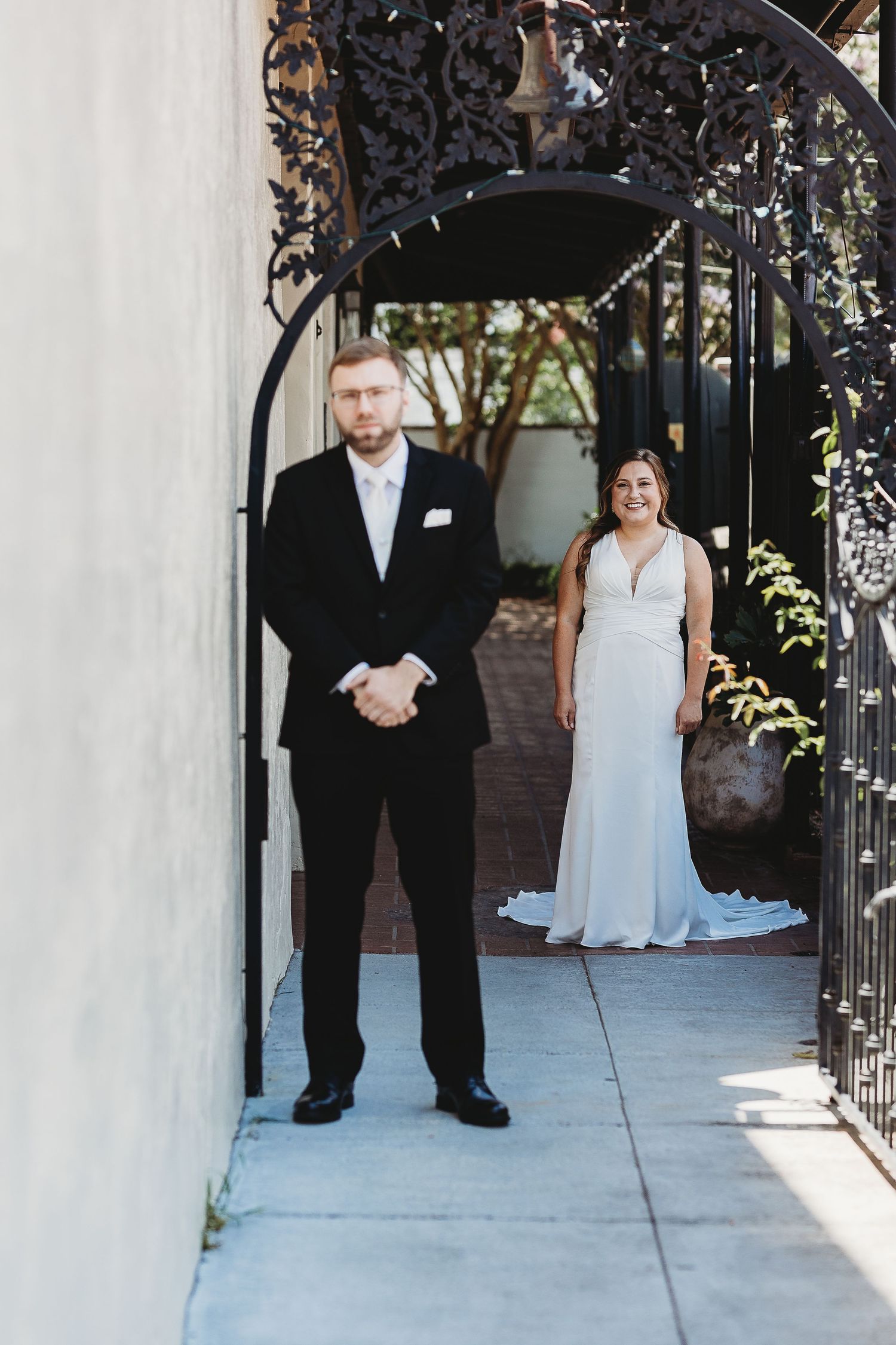 First look wedding moment under decorative black metal archway.