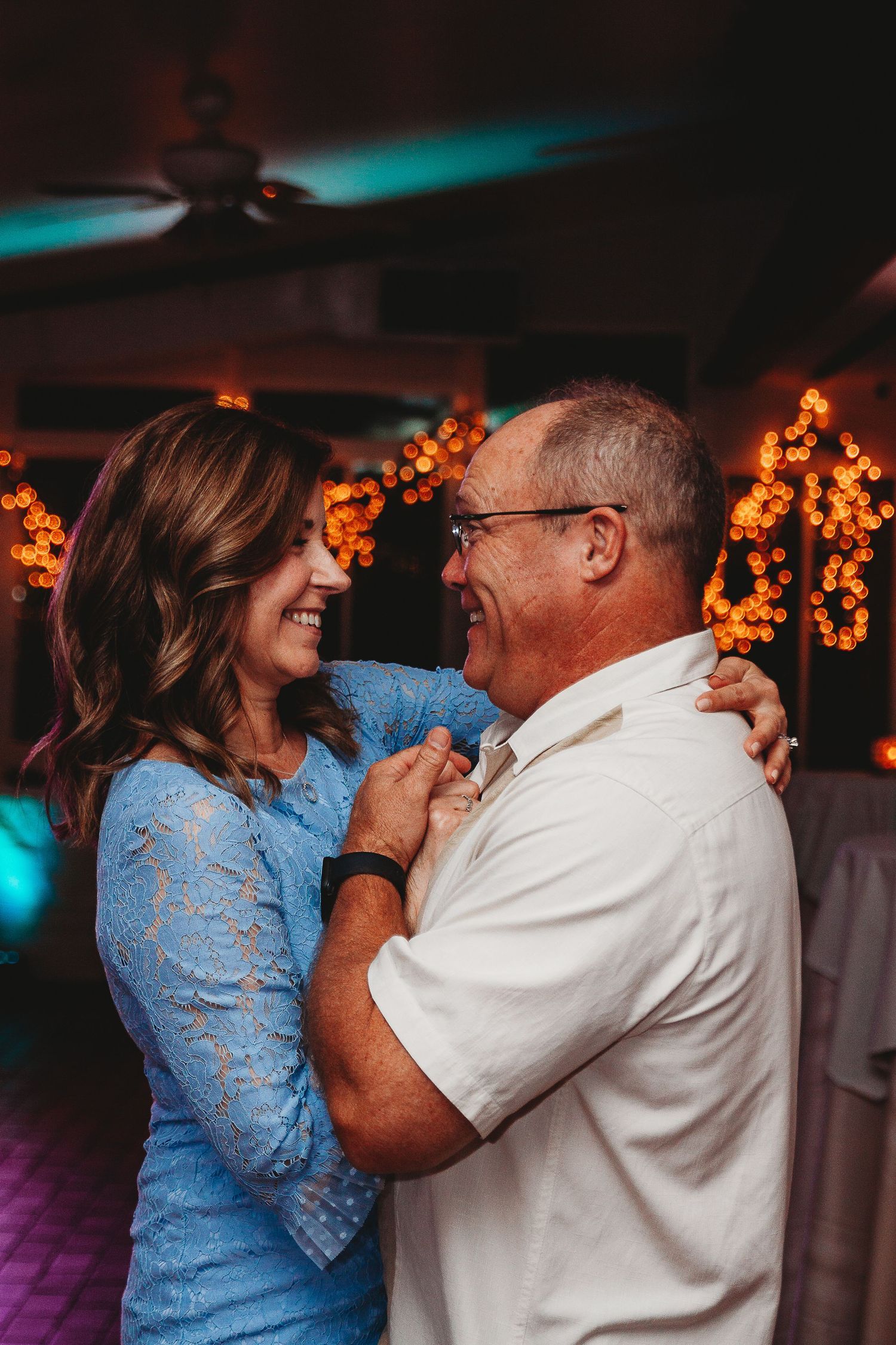 Couples dancing together at an evening reception with warm lighting and decorative elements.