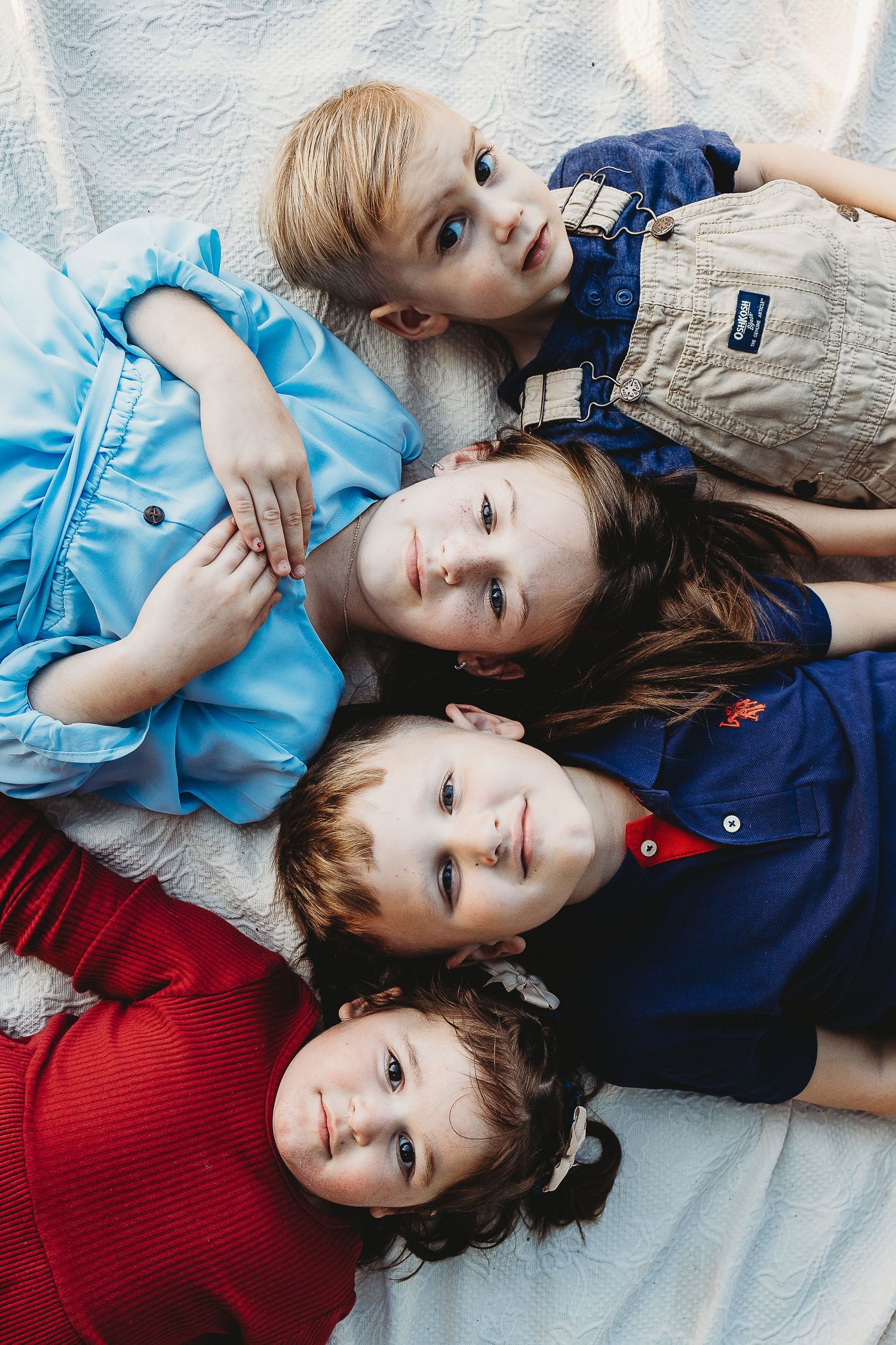 Children lying on blanket wearing coordinated blue and red outfits.