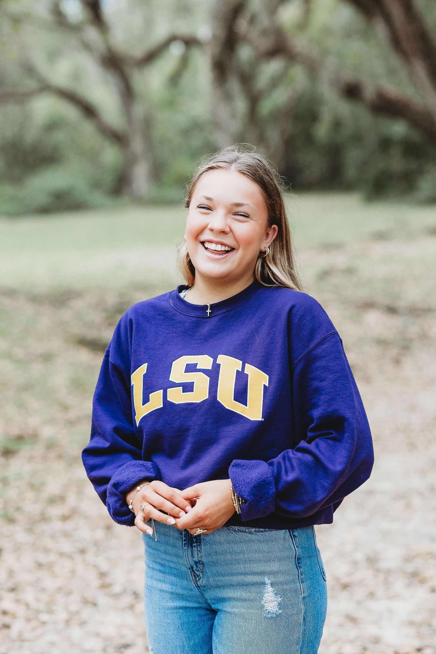 Person in blue LSU sweatshirt smiles during casual outdoor portrait session.