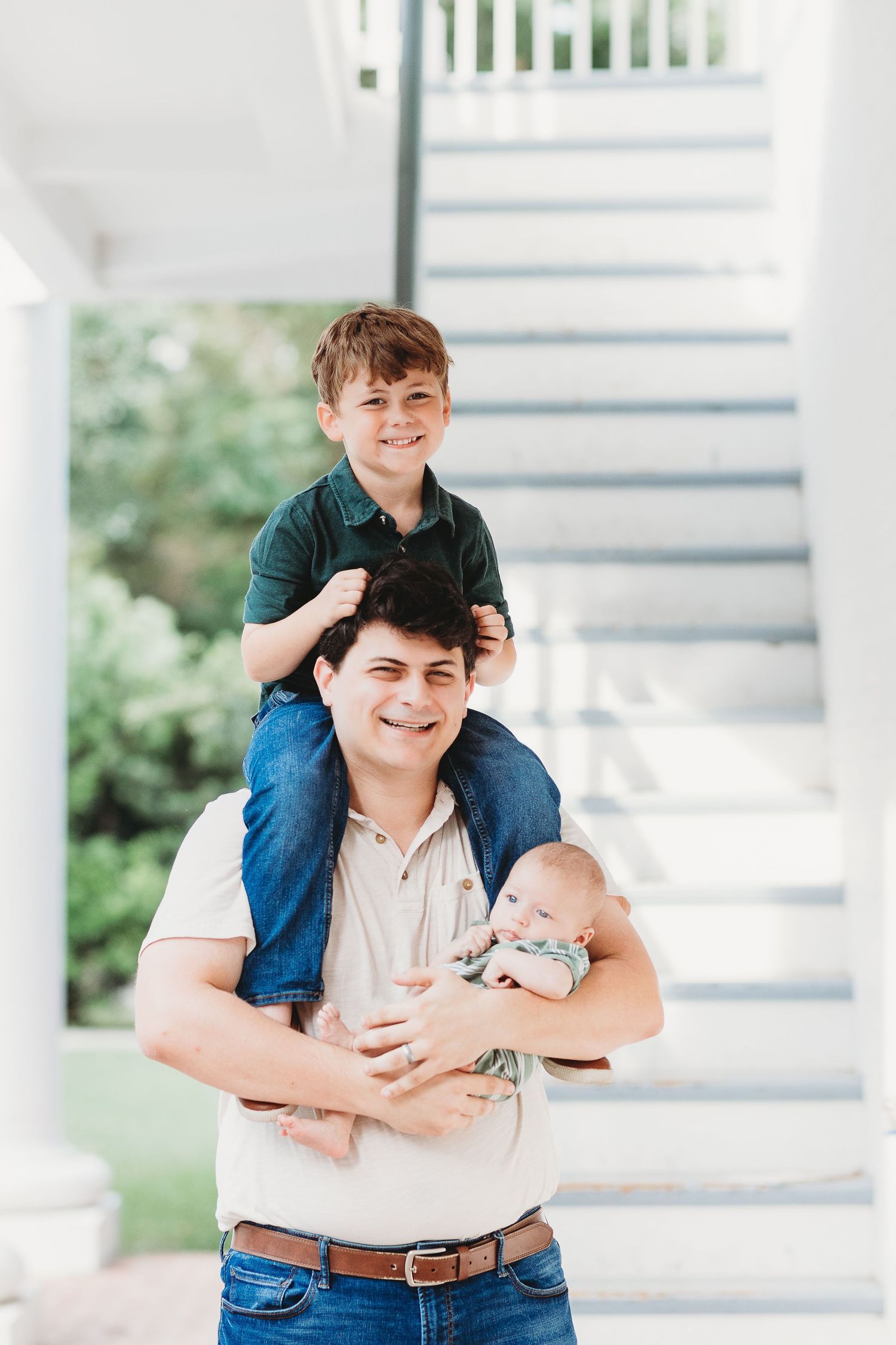 A playful family portrait on white stairs with natural lighting.