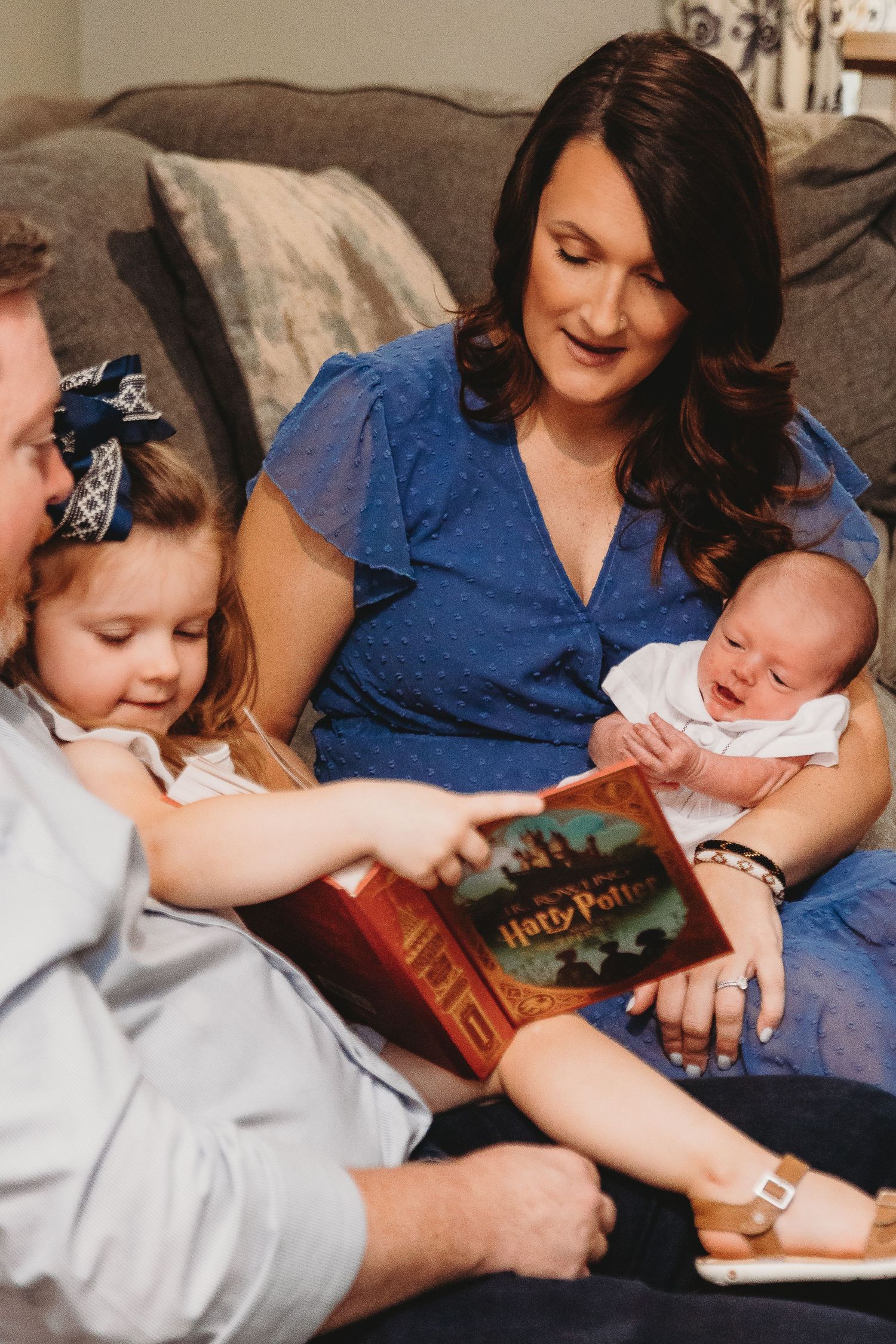 Family reading story book together while relaxing on couch.