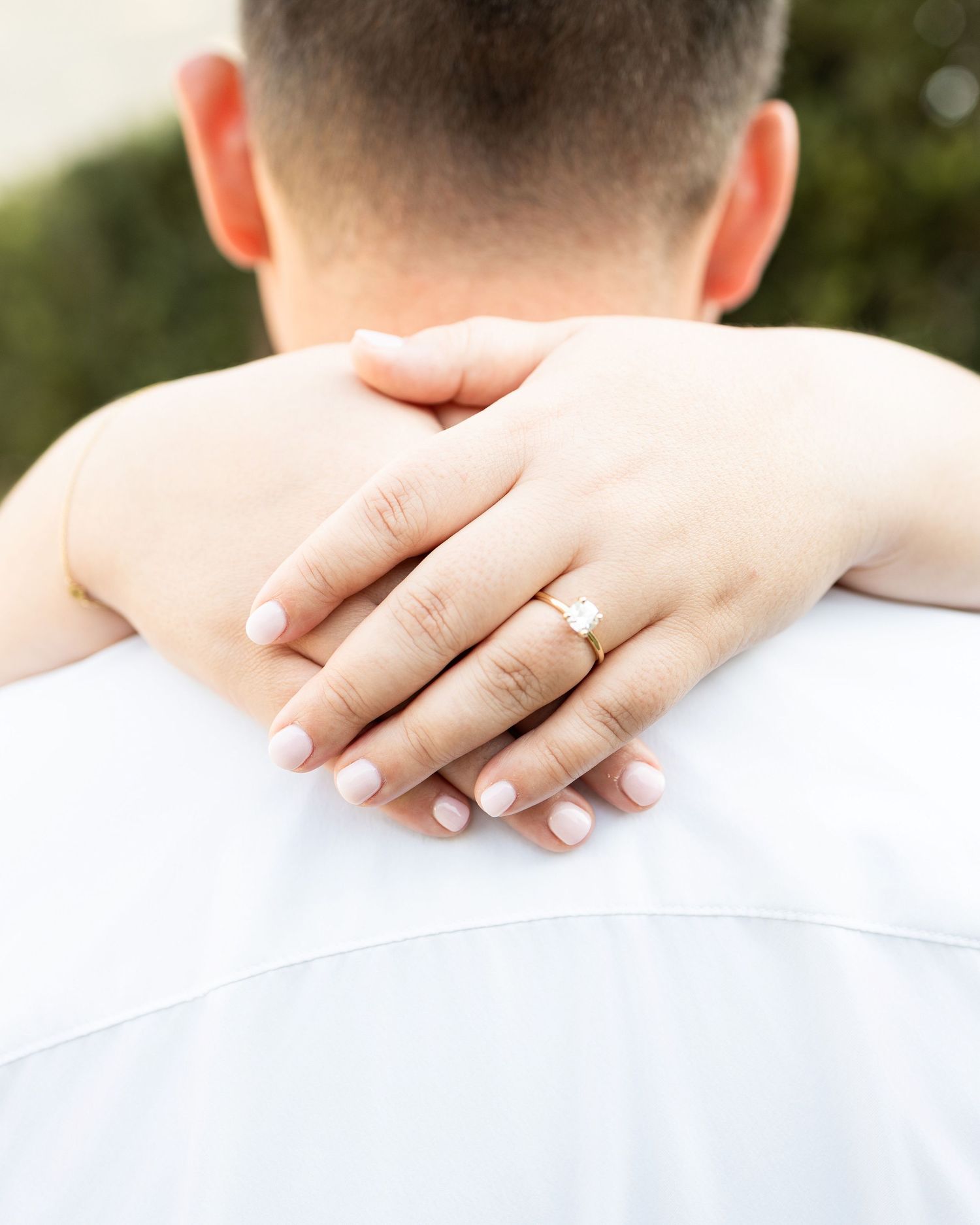 Close-up shots showing gentle hand placement on shoulders in white clothing outdoors.