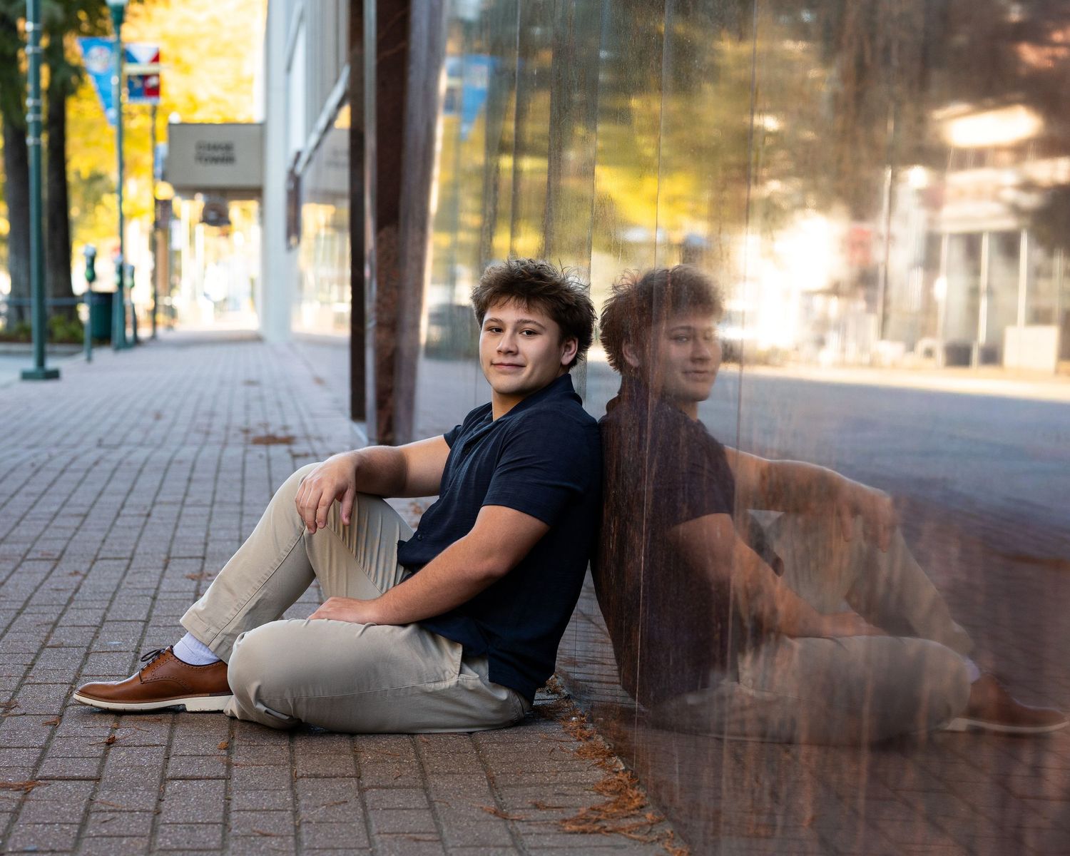 A creative composite photo shows multiple poses of a person lying on a sidewalk in an urban setting at sunset.