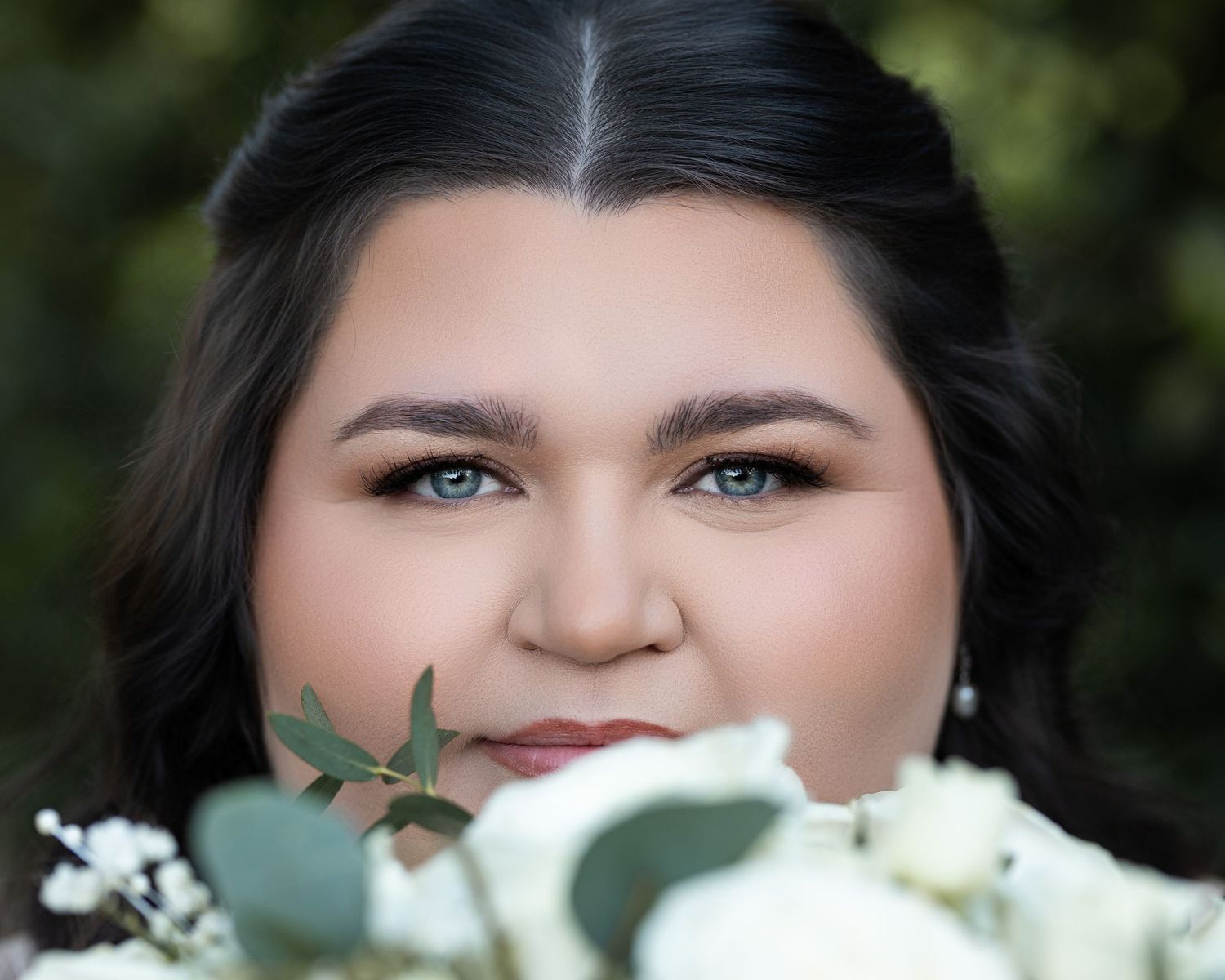 A close-up portrait shot with white flowers in the foreground creating a dreamy, romantic aesthetic.