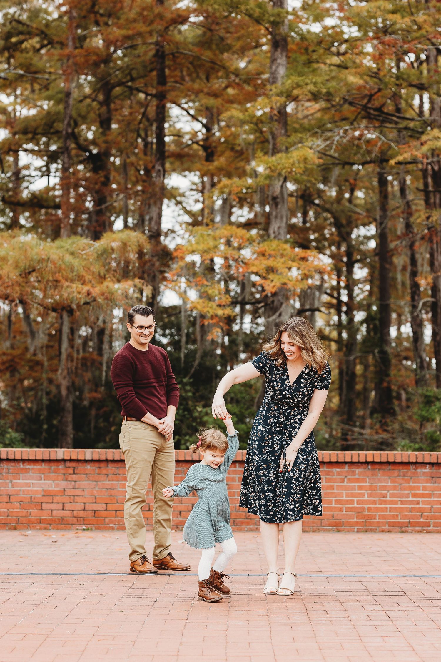 Family walking and playing together on a brick patio during a fall photoshoot.