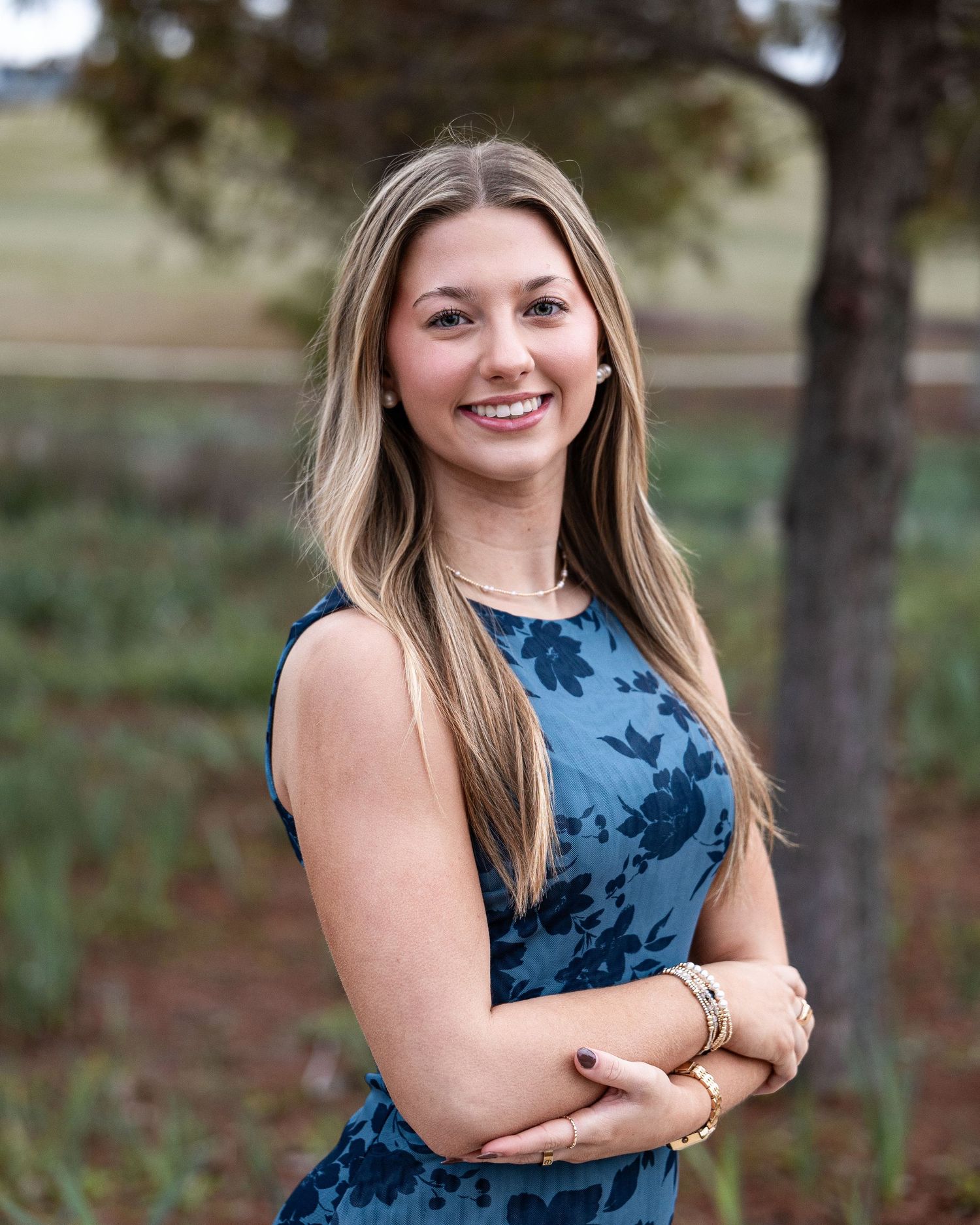 A person in a sleeveless navy blue floral dress poses outdoors against a natural background in multiple photos.