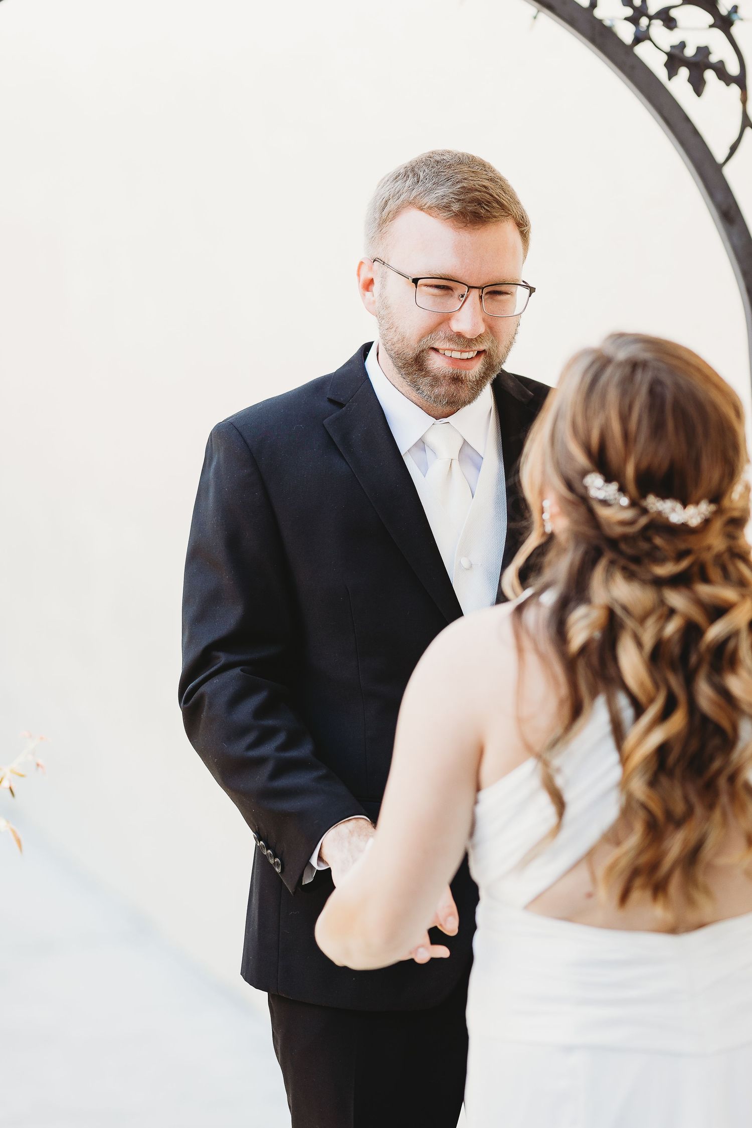 Intimate first look moment captured under decorative archway.