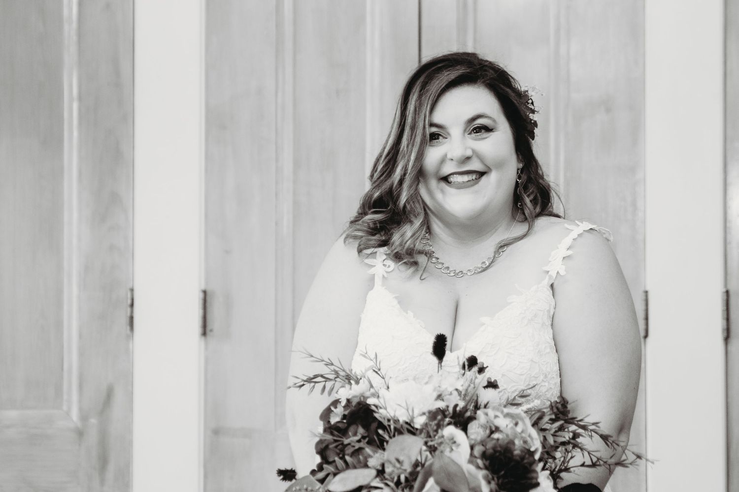 Black and white portrait of a bride holding an elegant floral bouquet.