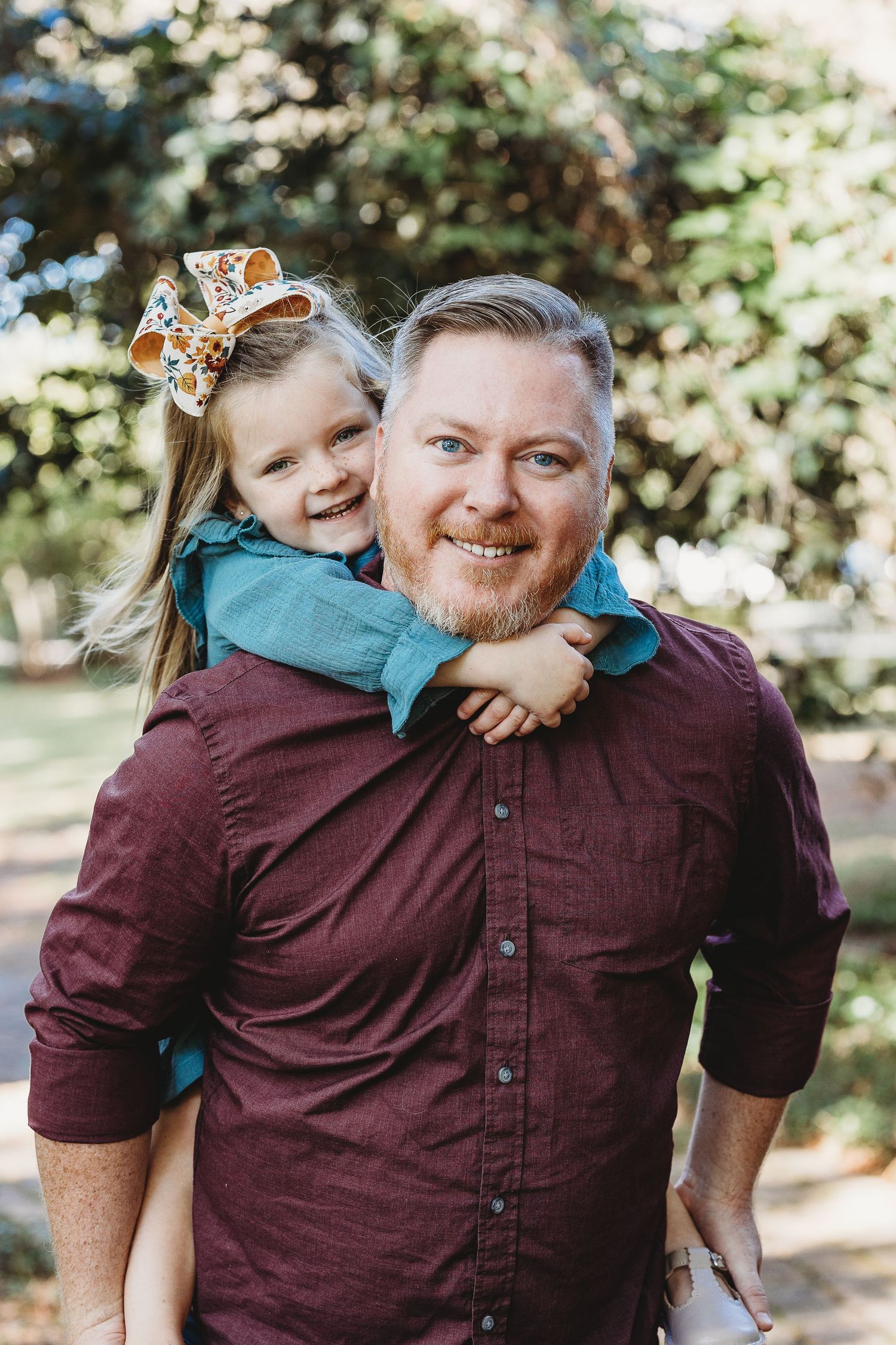A heartwarming outdoor portrait showing a playful piggyback moment in natural lighting.