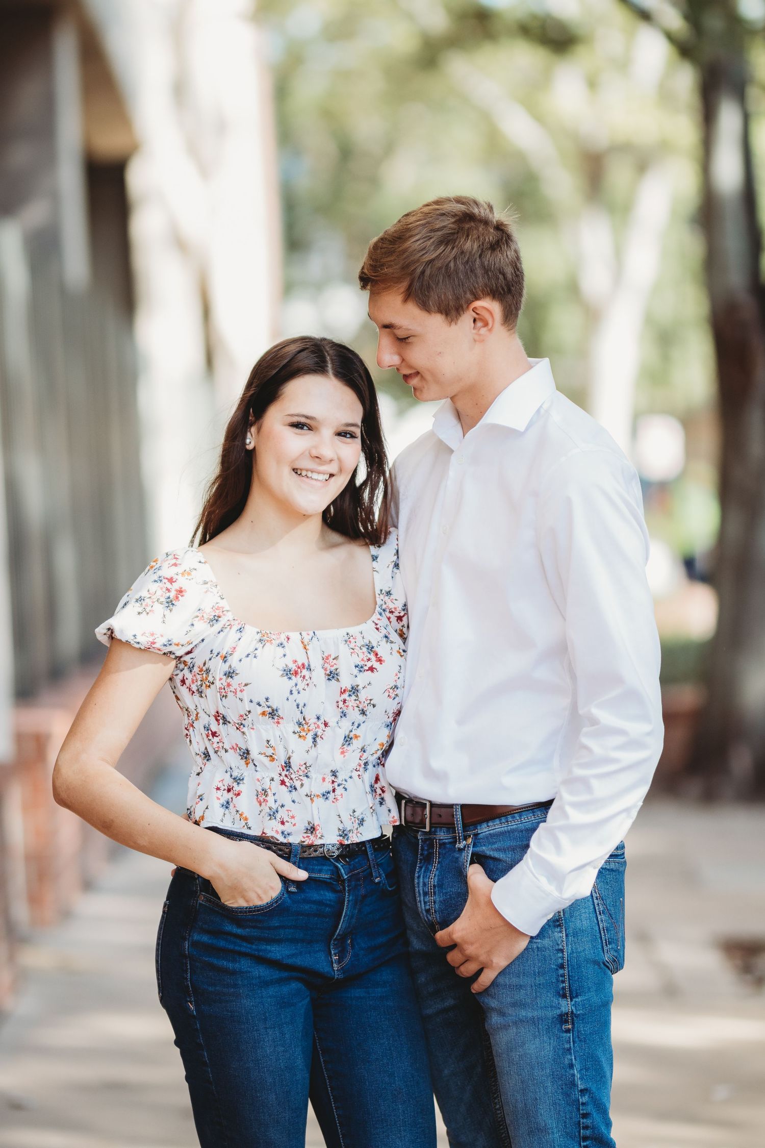 A couple in casual attire shares intimate moments while walking through a columned pathway.