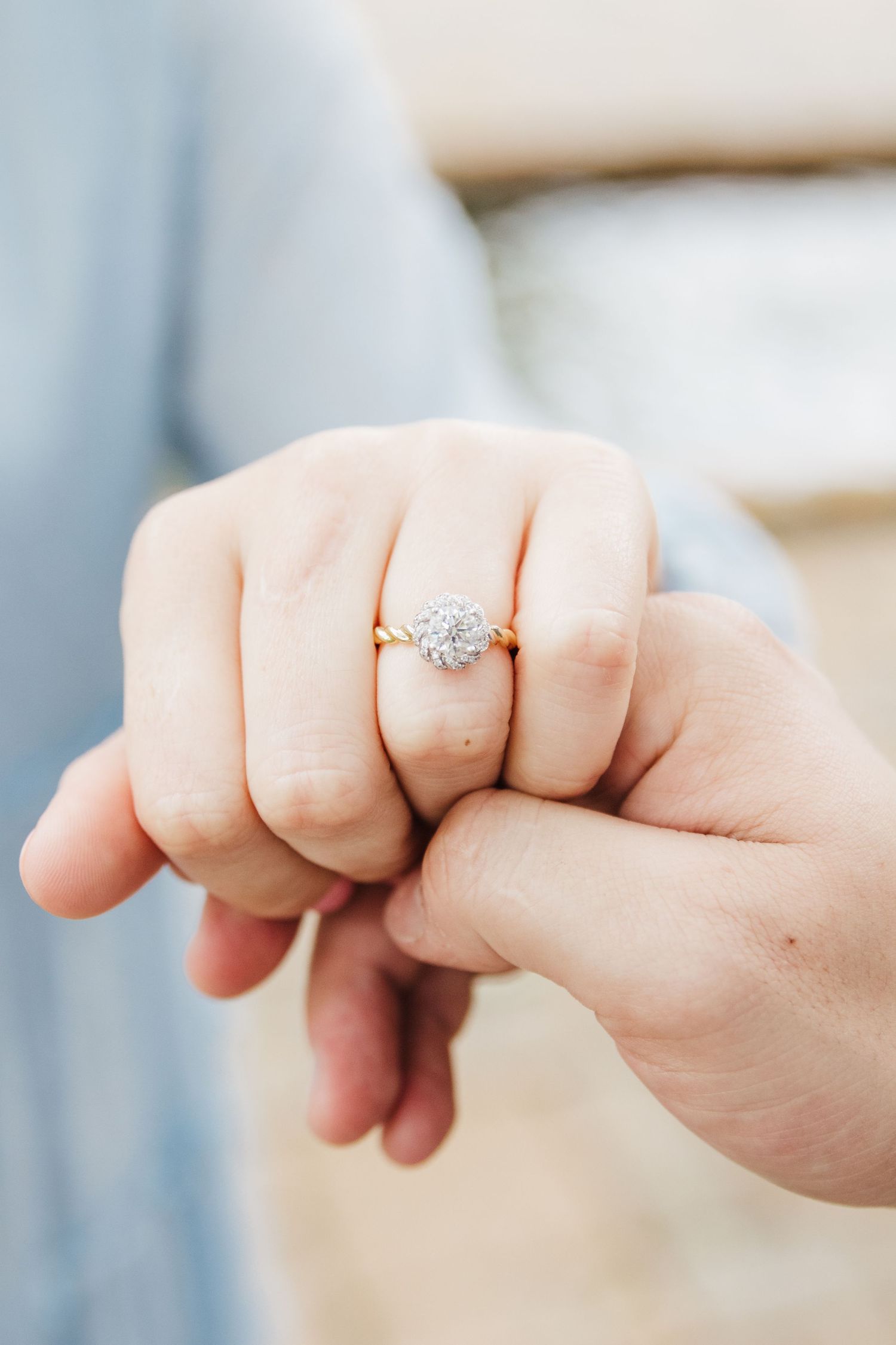 Close-up of hands showing off a sparkling engagement ring.