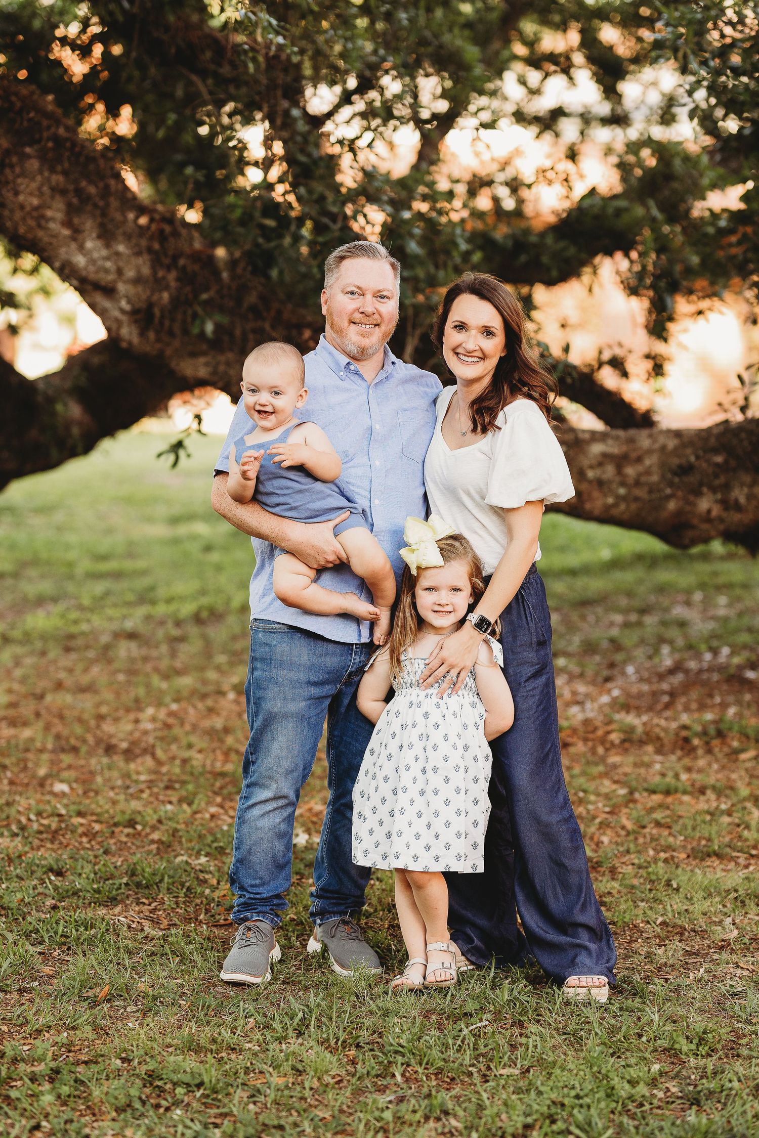 Family group portrait under a large tree during golden hour.