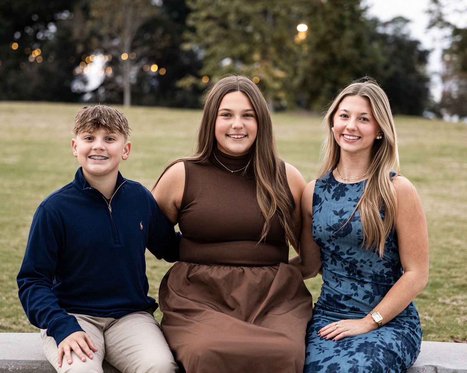 Family wearing coordinated blue and brown outfits poses together outdoors for professional autumn photos.