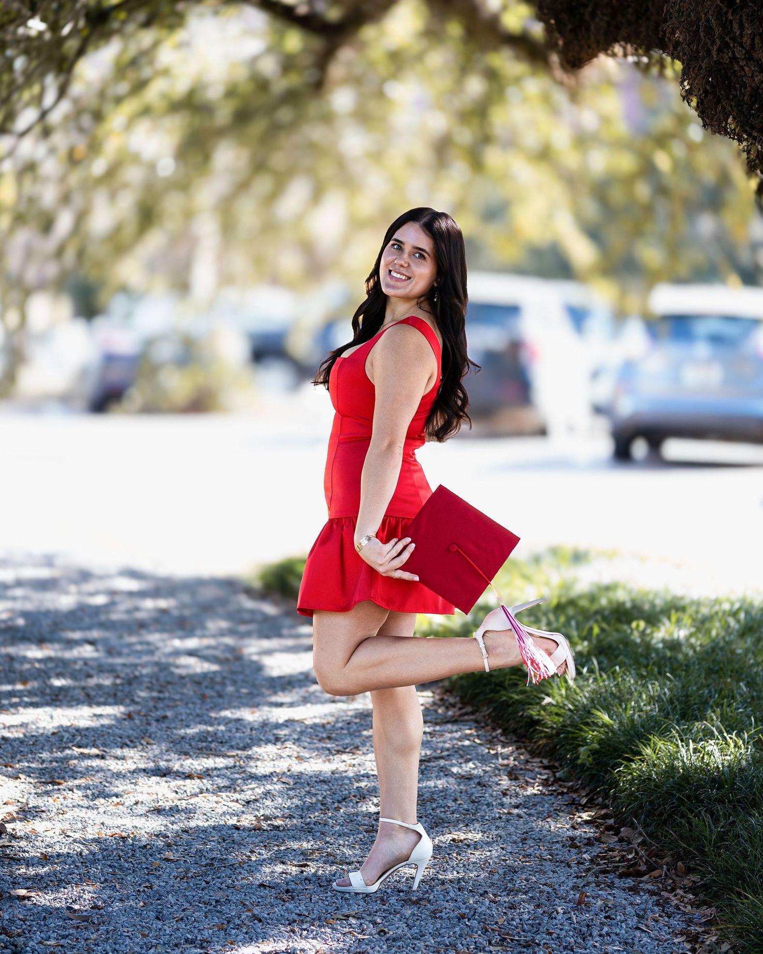 A woman in a red dress and beige heels poses gracefully in a series of outdoor shots on a sunlit path.