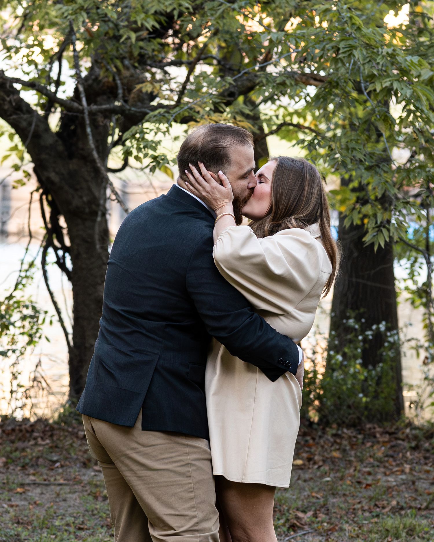 Couple sharing a romantic moment together in an autumn forest setting with golden leaves in the background.