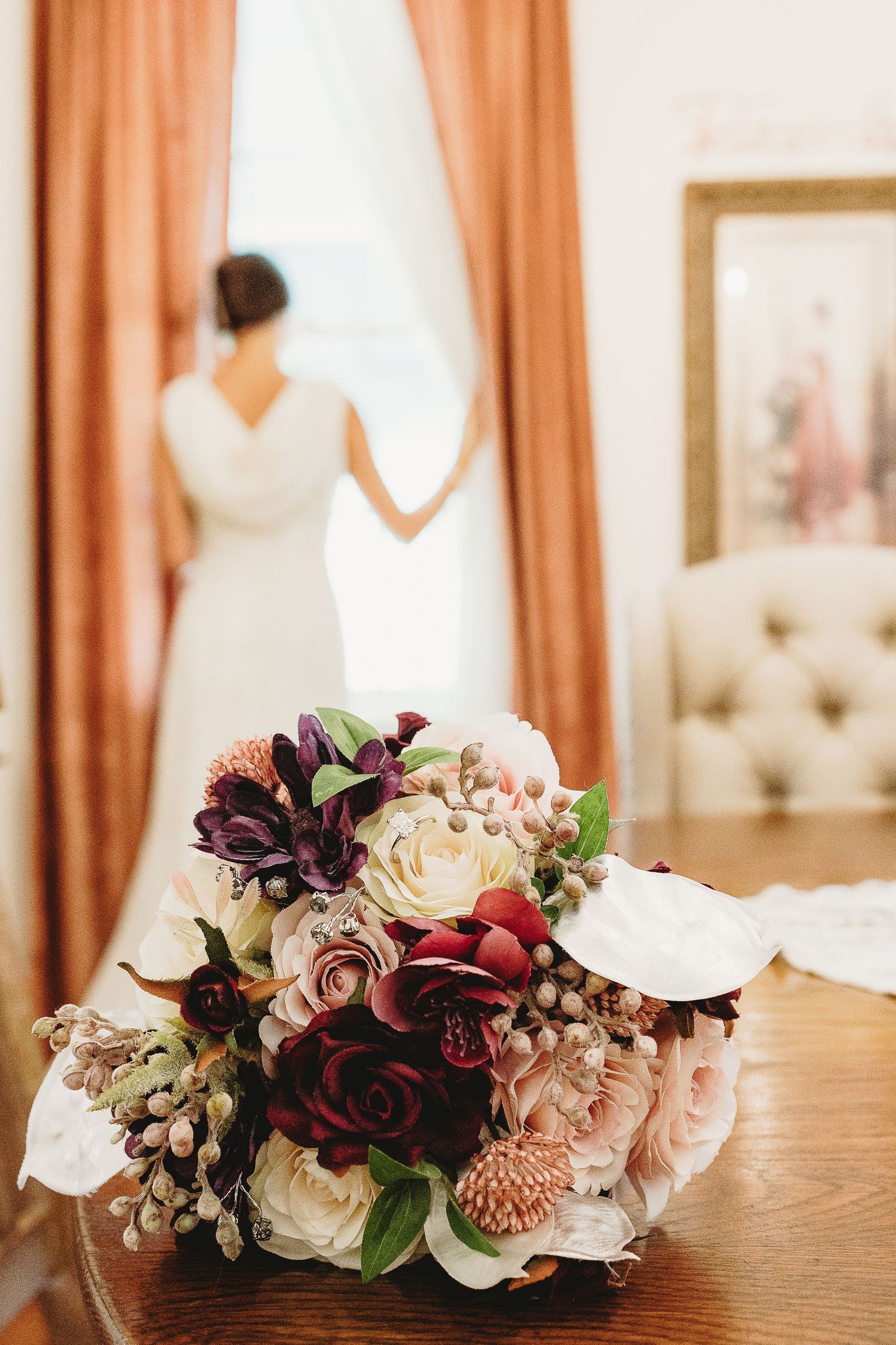 Beautiful wedding floral arrangements with burgundy and blush roses on wooden surface.