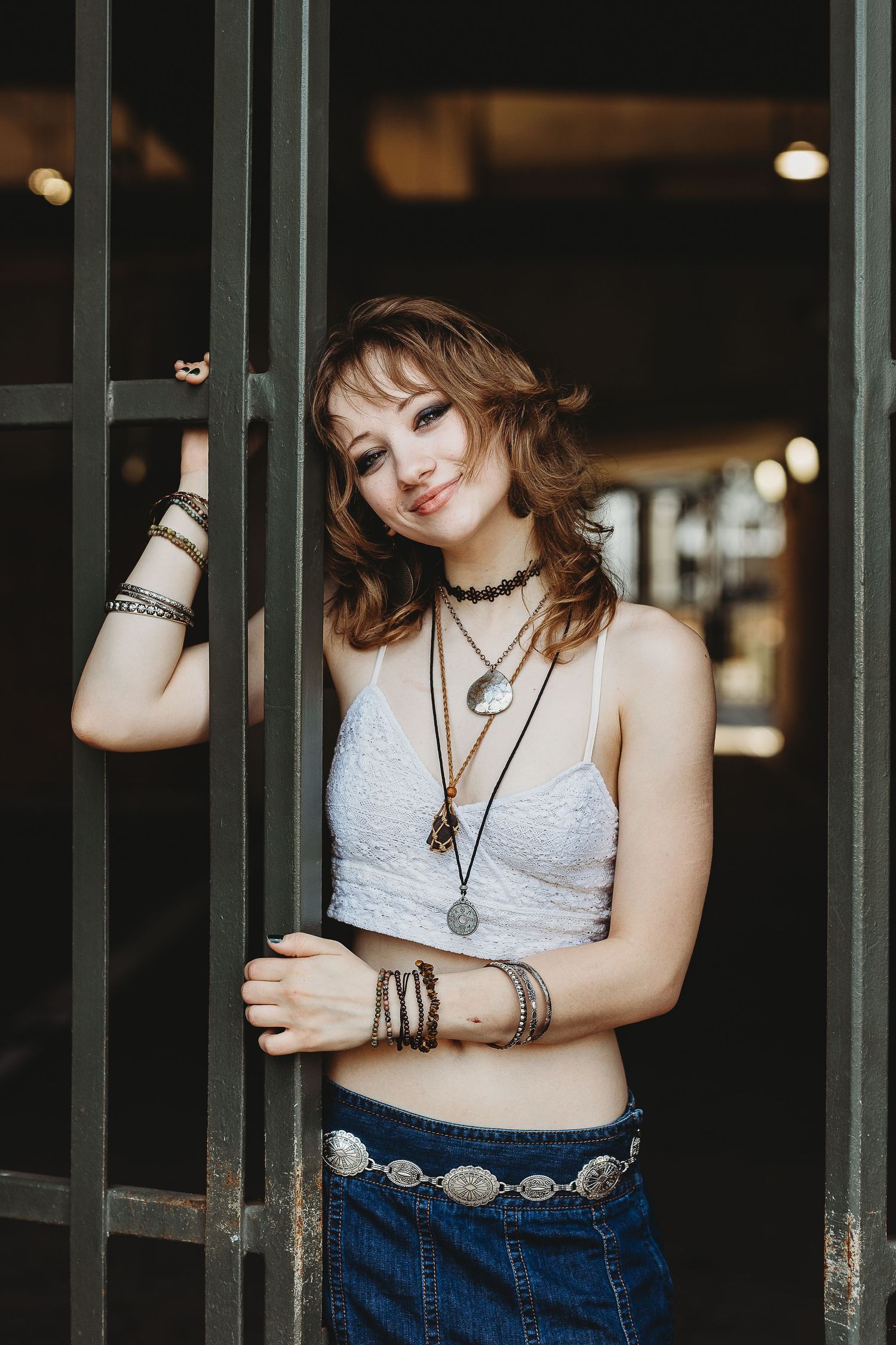 Bohemian style portrait with model wearing layered necklaces and crop top by metal doorway.