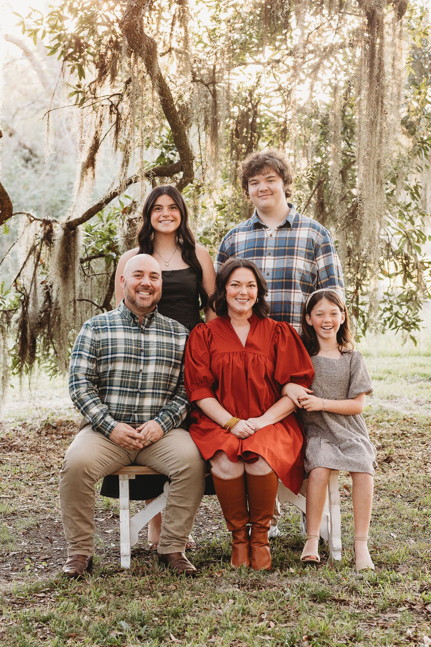 A family photo session in a wooded setting with everyone wearing plaid shirts and casual attire.