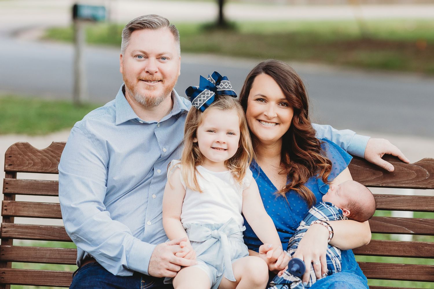 Family members relaxing on a wooden bench during an outdoor portrait session.
