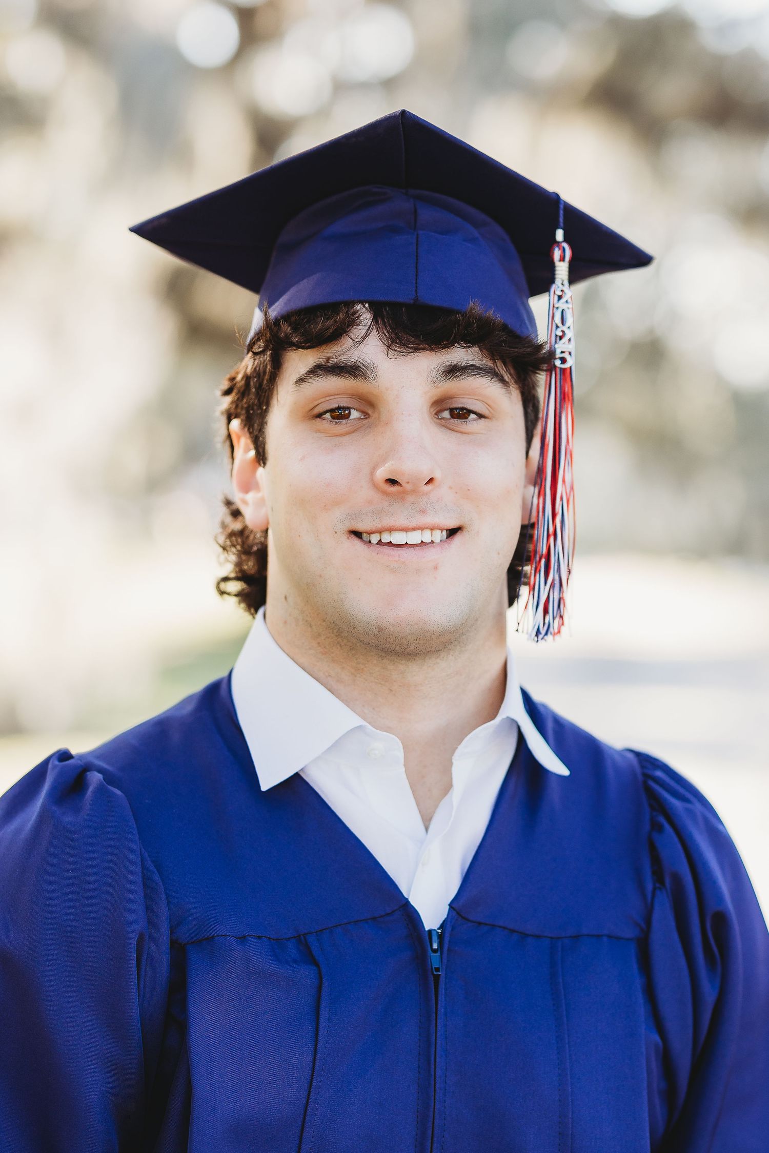 Graduate in blue cap and gown poses for commemorative photos outdoors.