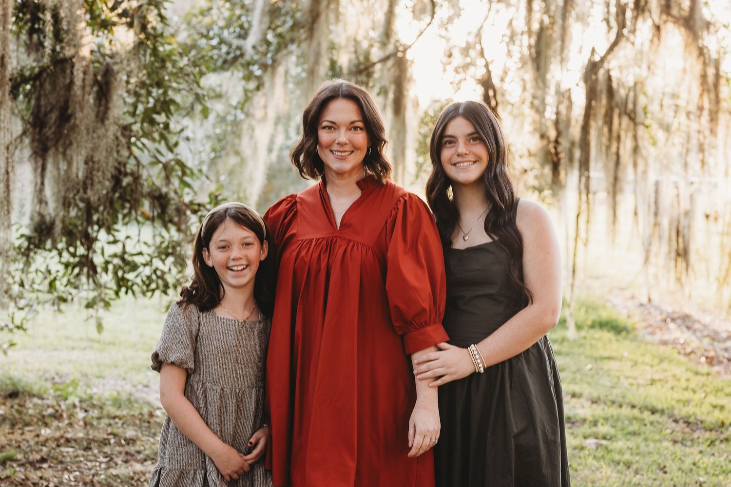 Family portrait series in coordinated outfits against natural outdoor backdrop.