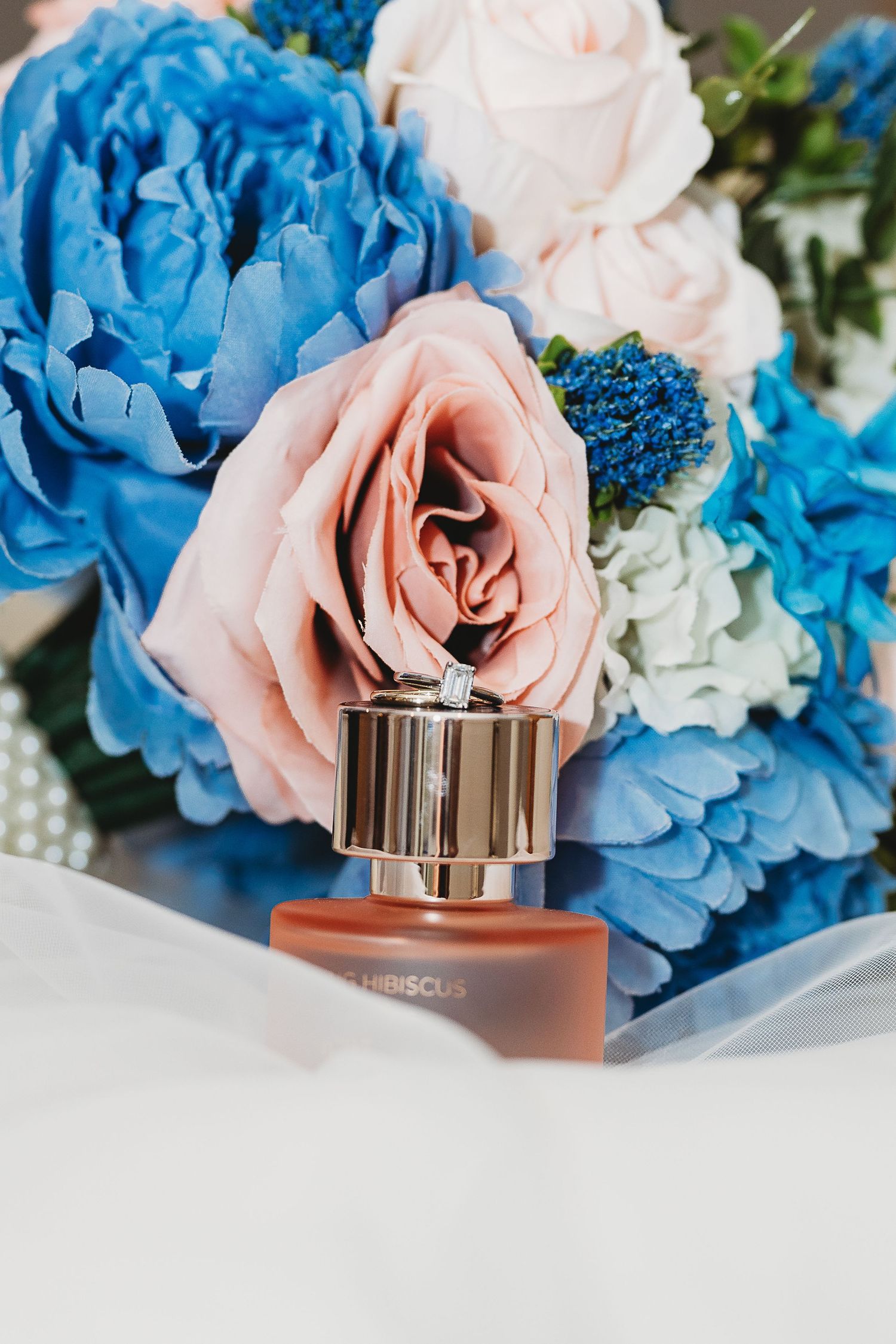Wedding bouquet with blue and pink roses styled with perfume bottle.