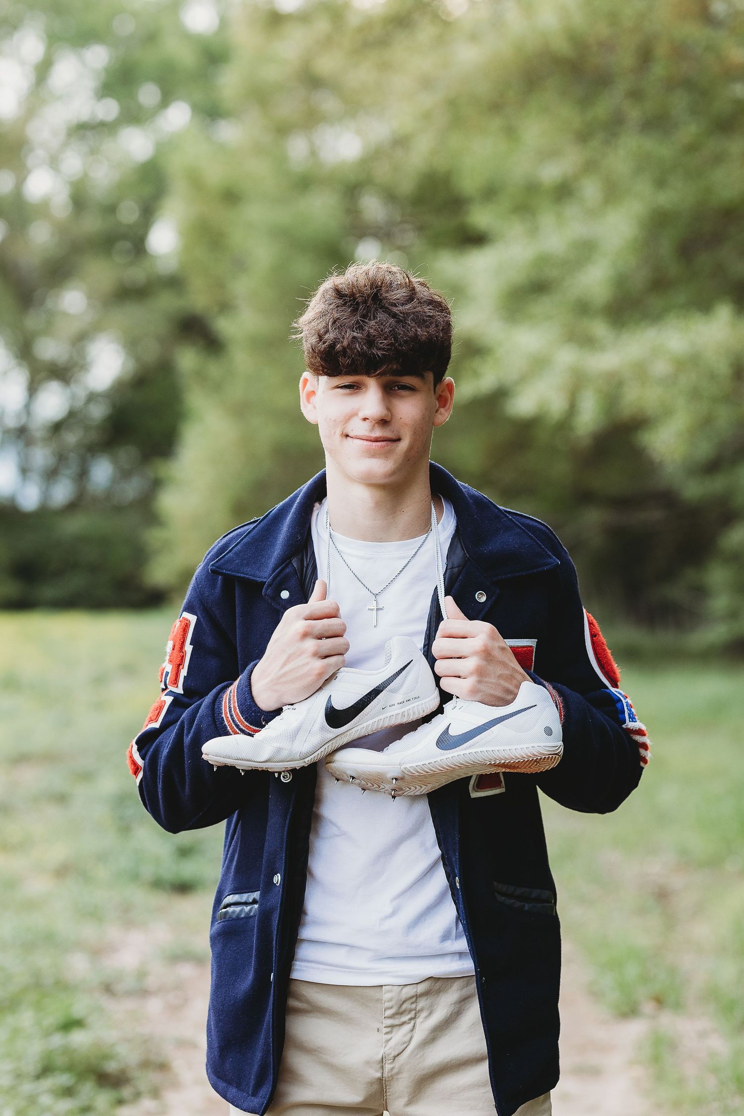 Person in navy jacket showing off white Nike sneakers in outdoor setting.