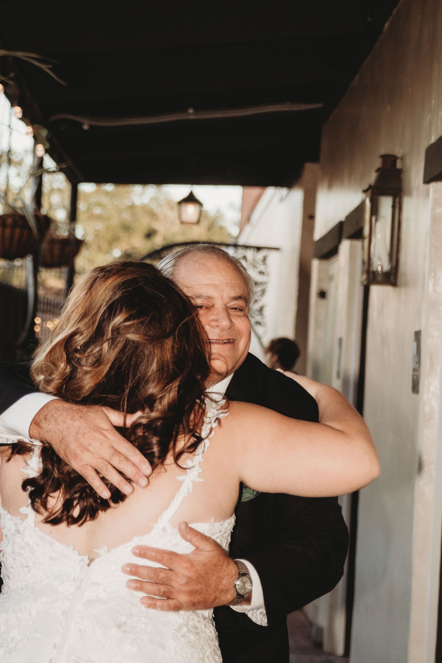 A heartfelt embrace at a wedding venue with white columns and warm lighting.