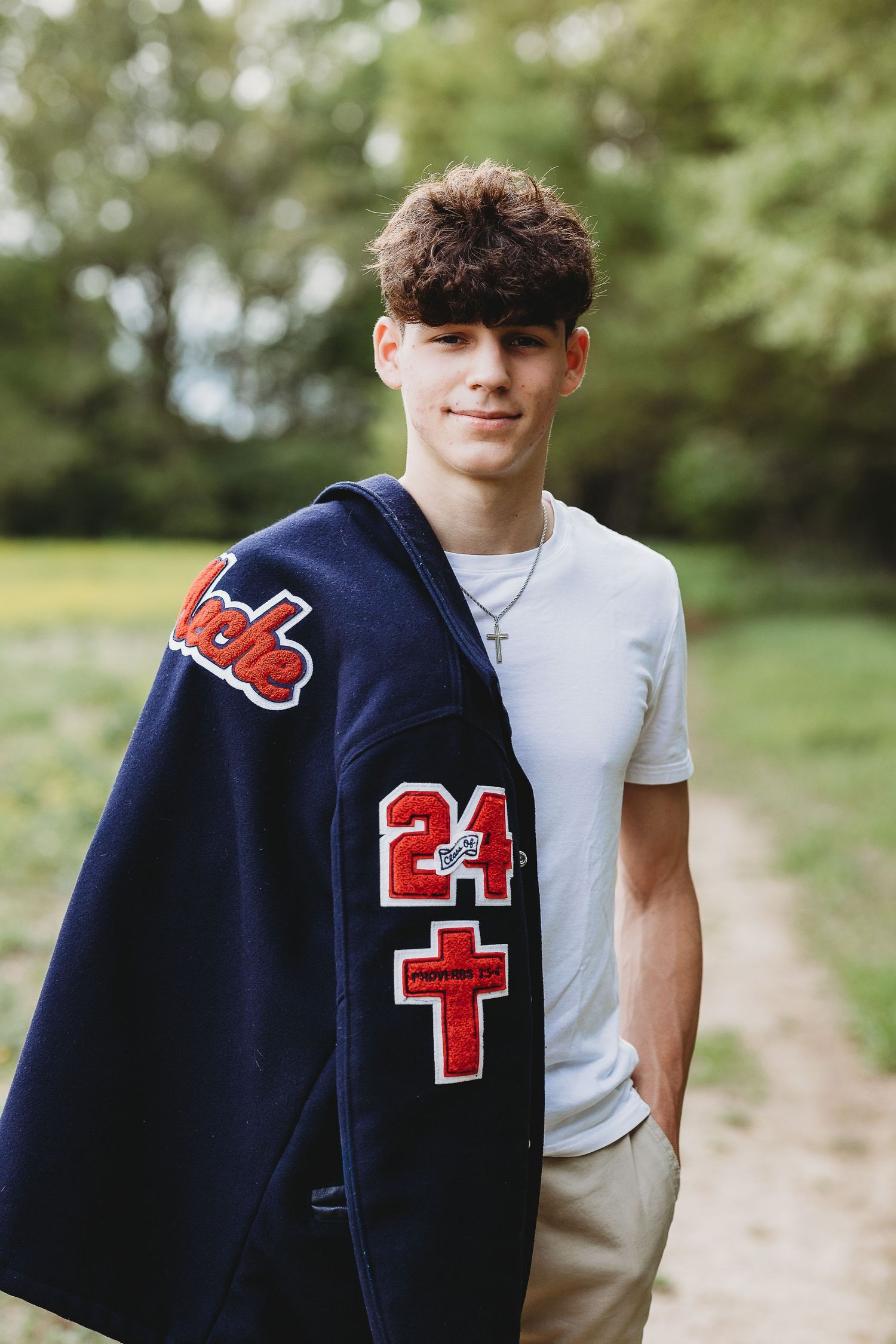 Navy letterman jacket with red varsity numbers and patches shown in detail against outdoor background.