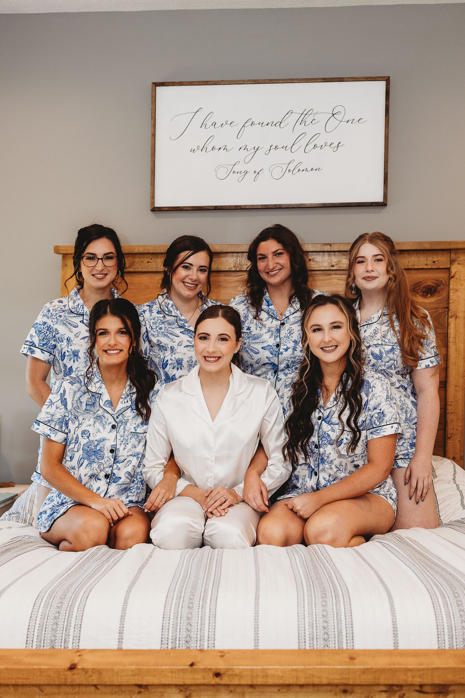 Bridal party lounging on wooden bed frame in coordinated blue floral robes.