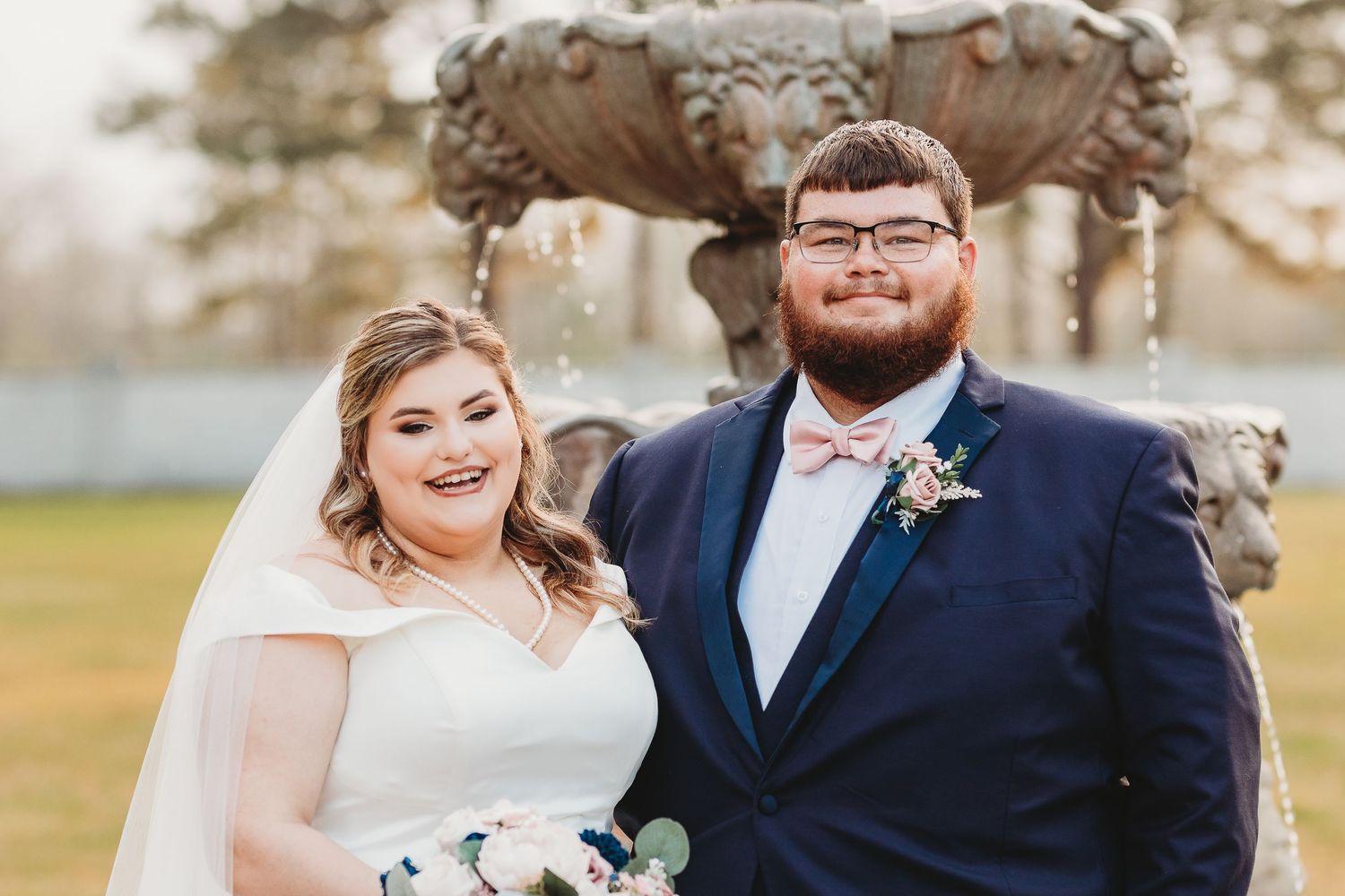 Wedding party members smile during formal photos at an outdoor venue.