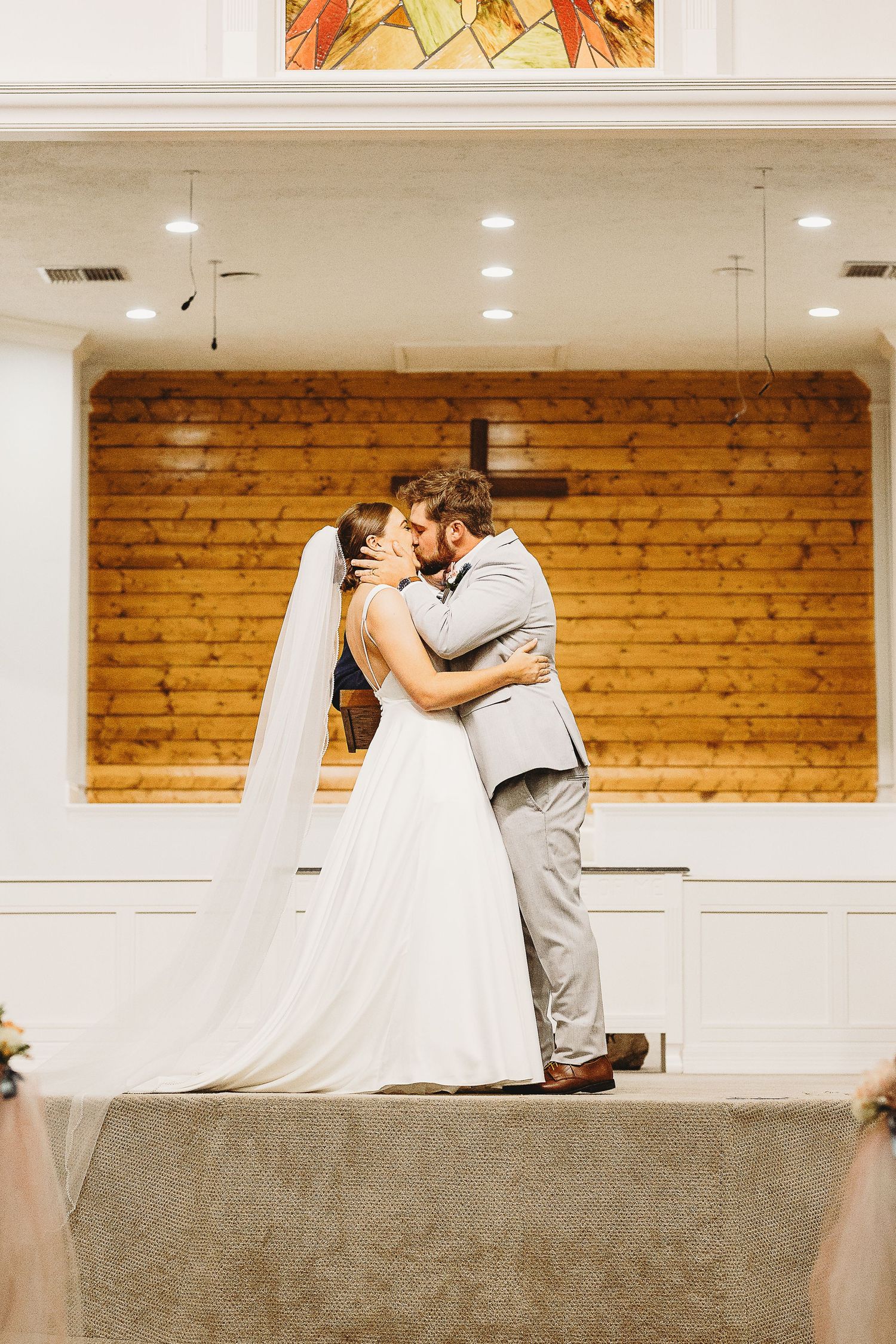 A romantic wedding ceremony moment in a rustic venue with wooden walls and white draping.