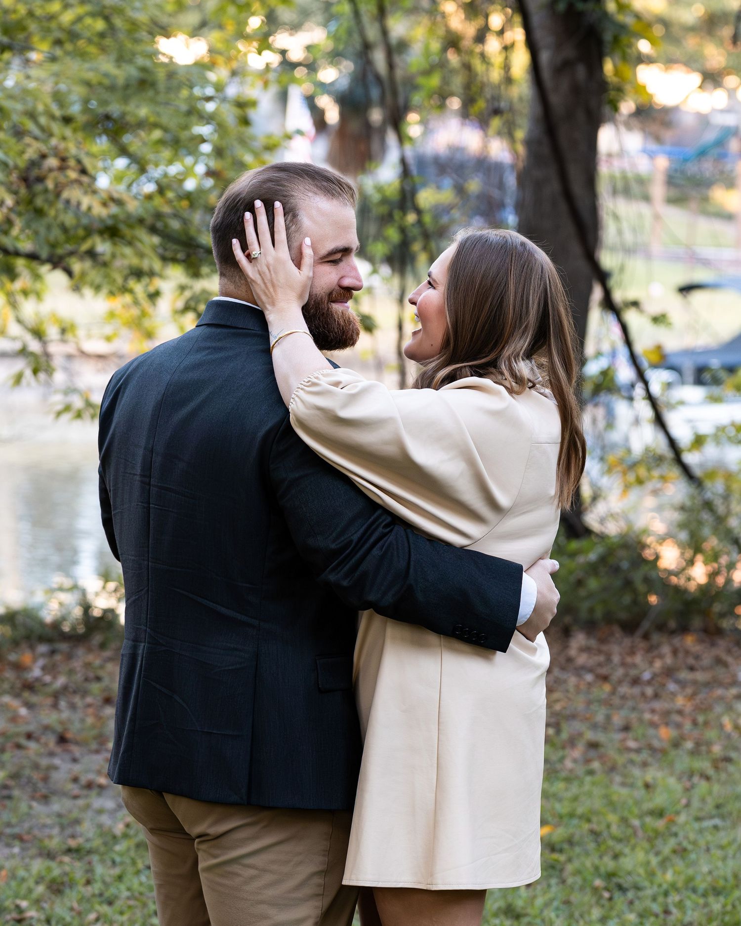 A couple shares a tender moment together in an autumn outdoor setting with fallen leaves on the ground.