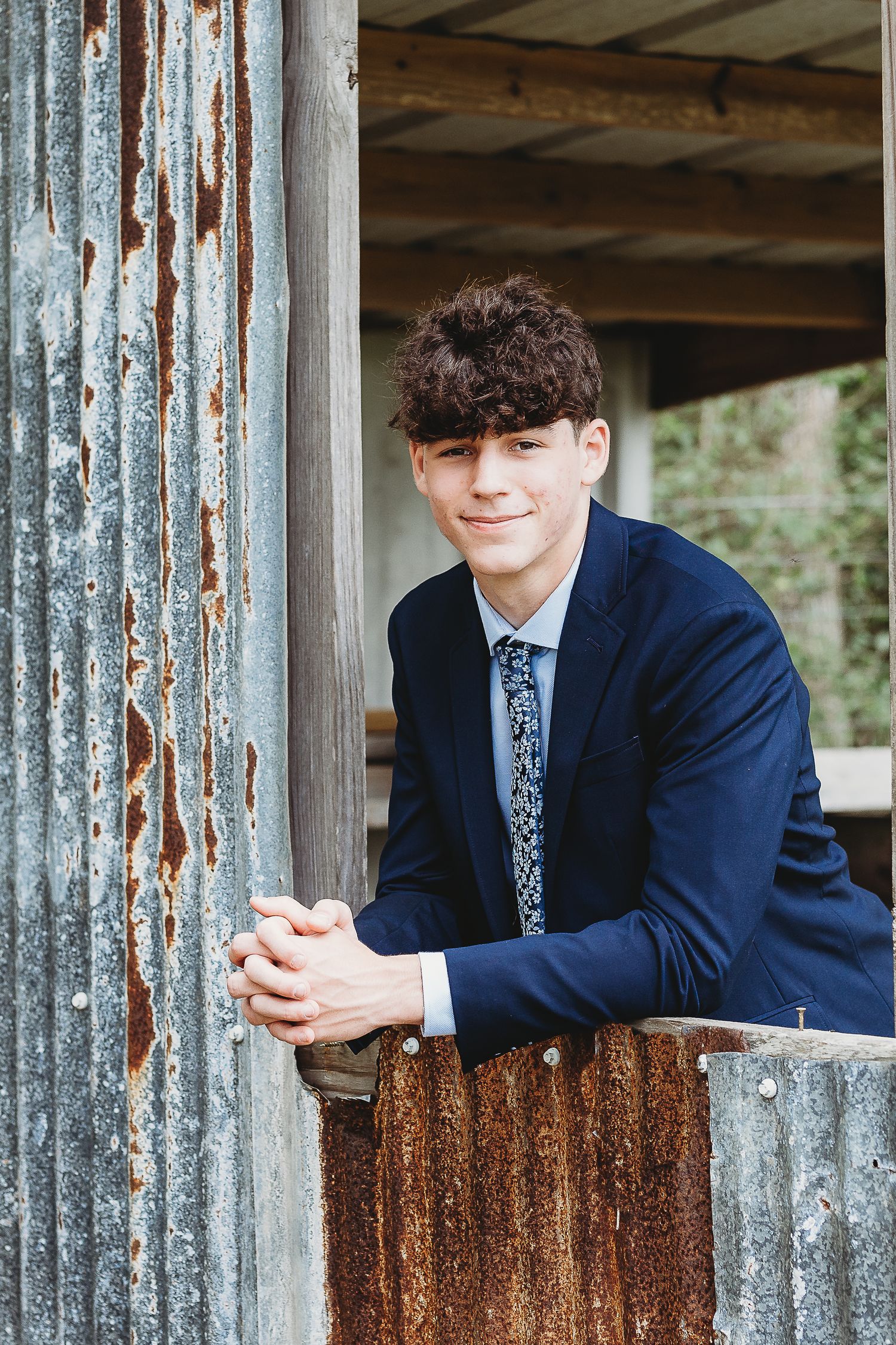 Creative portrait through rustic metal panels showing person in navy suit.