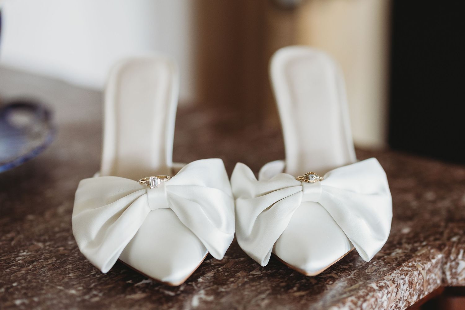 Elegant white bridal shoes with bow details on textured surface.