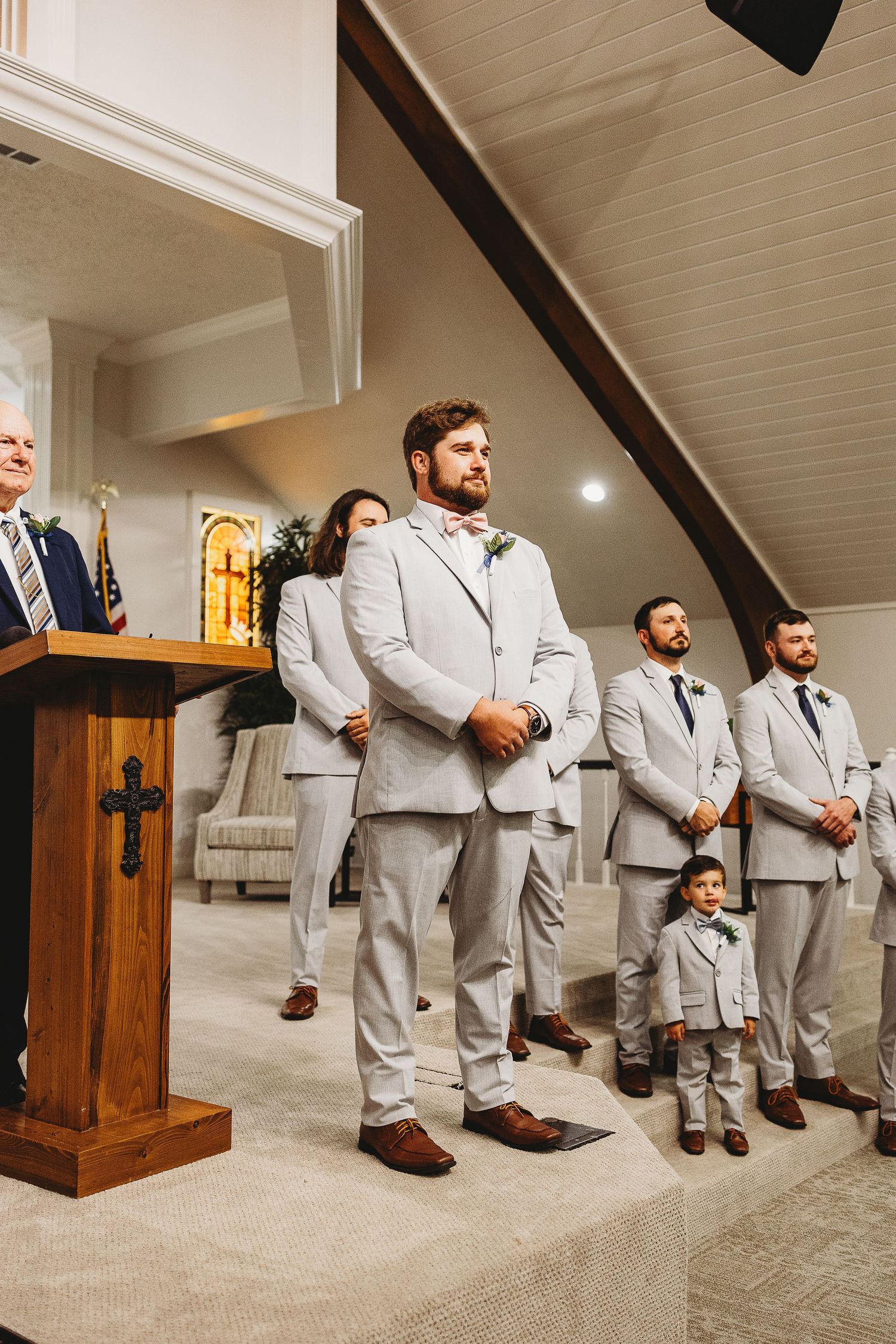 Wedding party members in gray suits arranged on church steps for creative group photos.