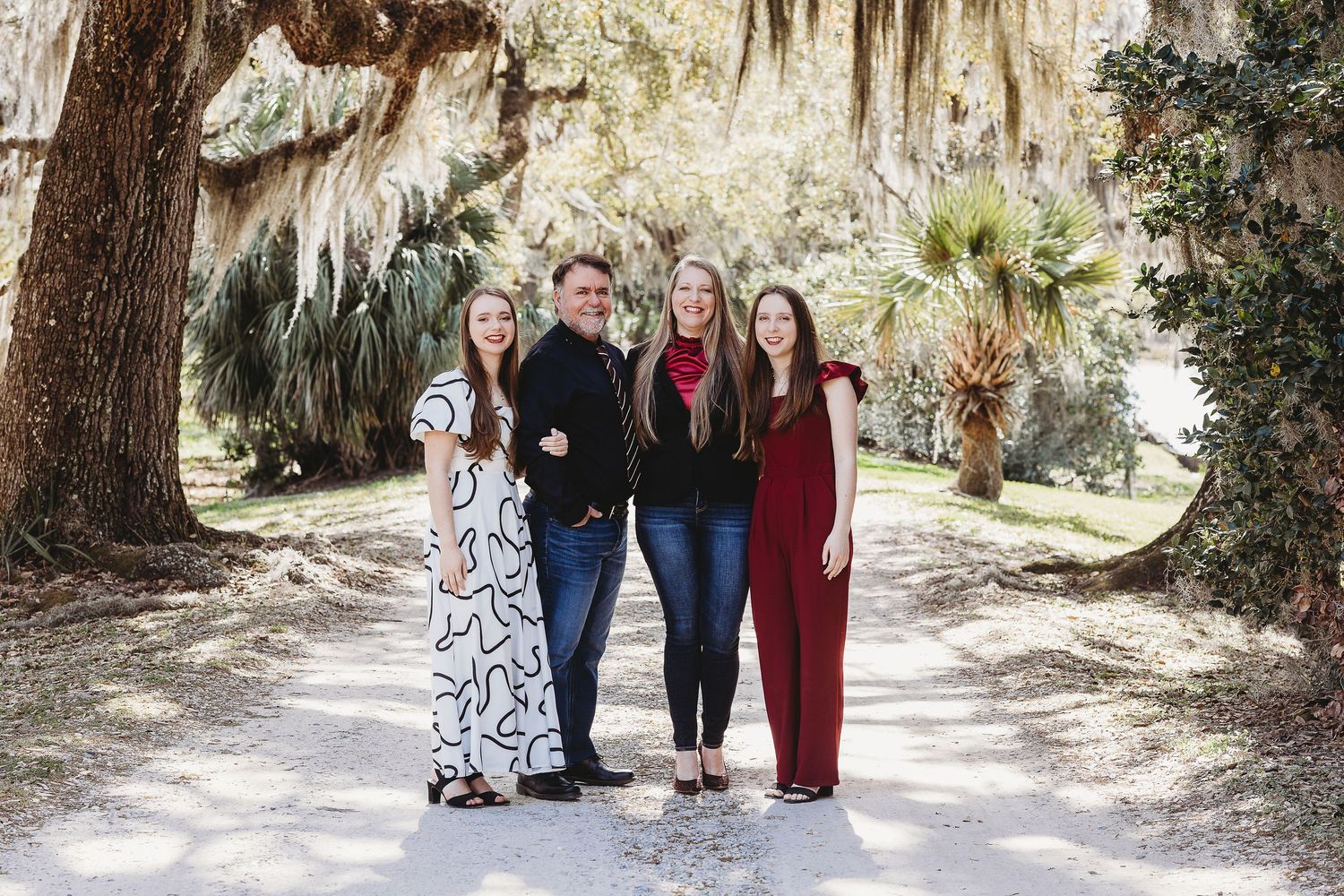 A family portrait session under oak trees with Spanish moss in a natural outdoor setting.
