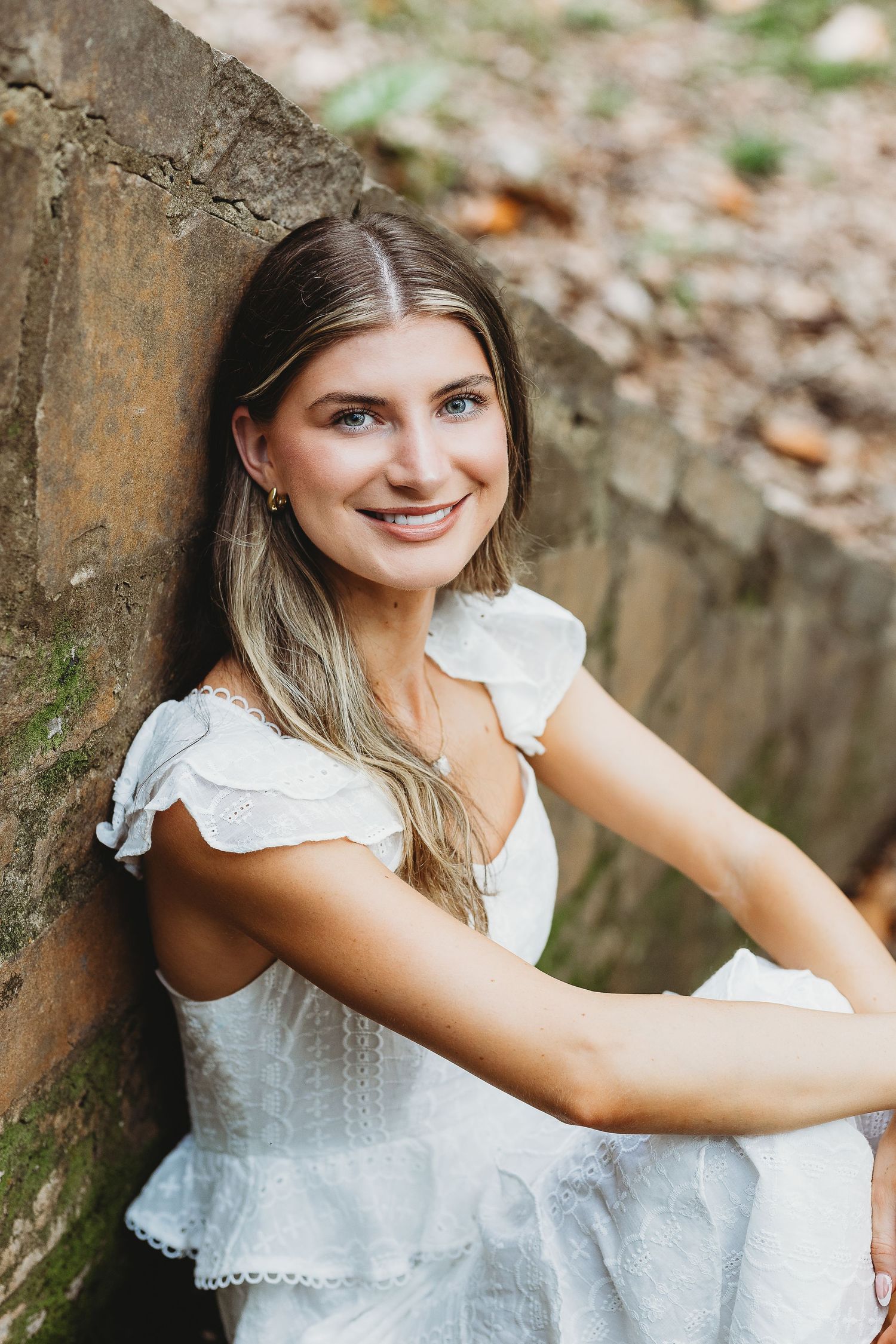 Portrait series featuring someone in a white eyelet dress against a rustic outdoor backdrop.