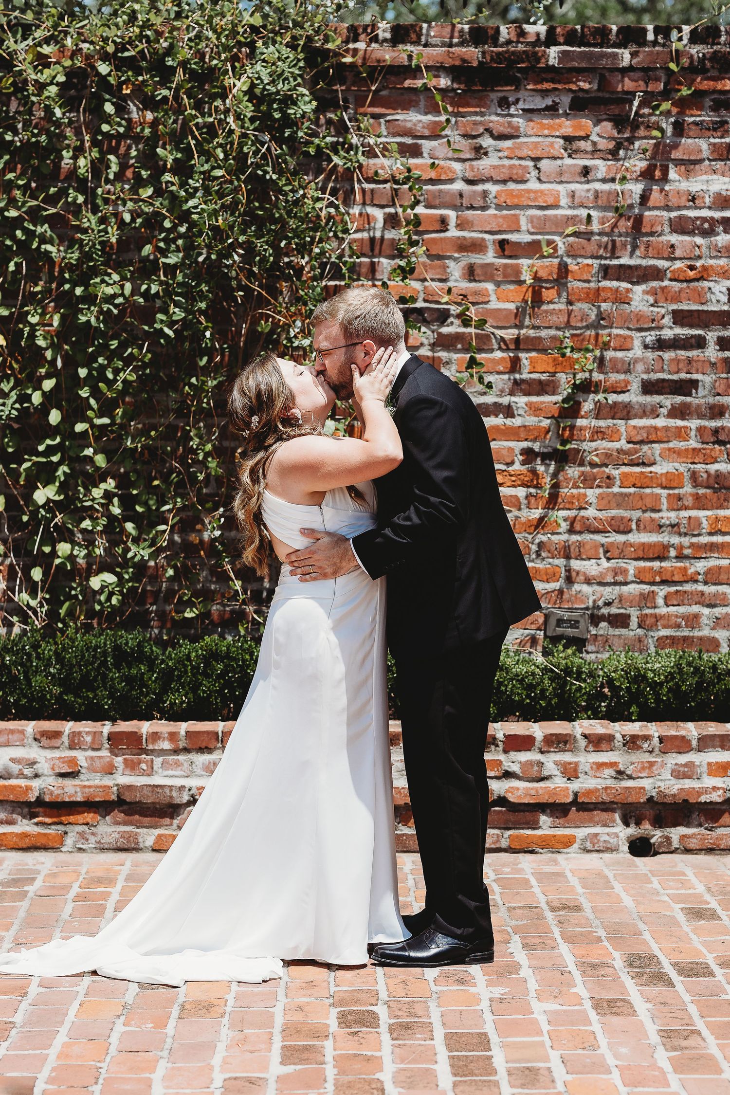 Romantic wedding first look sequence against a rustic brick wall with greenery.
