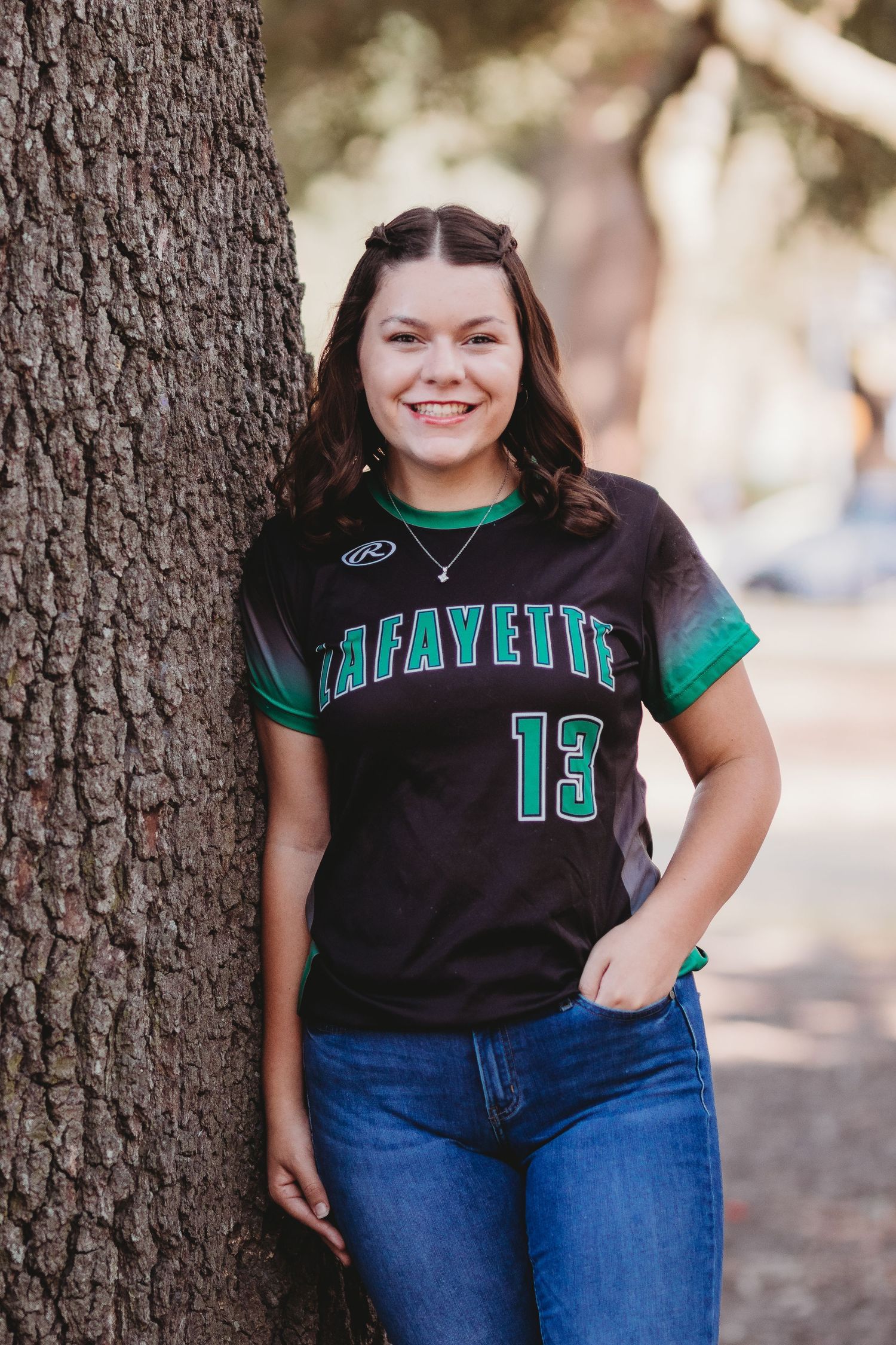 A casual portrait against a tree wearing a Lafayette #13 sports jersey and jeans.