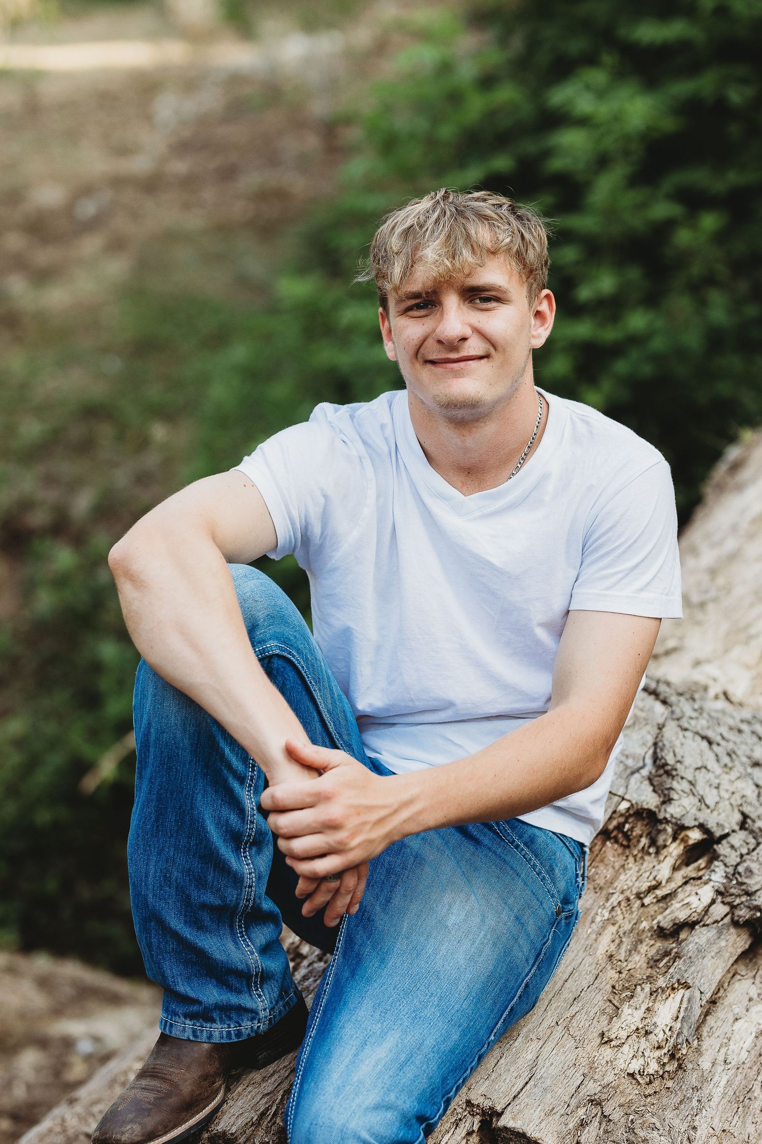 Casual portrait session on fallen tree trunk in outdoor setting with natural lighting.