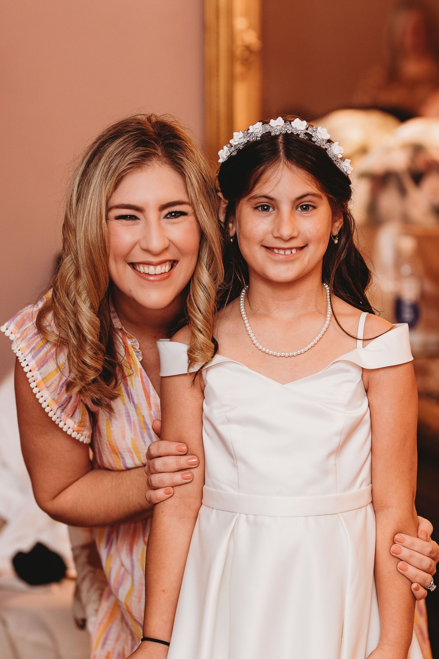 Young attendants in white dresses and pearls share joyful moments at a wedding celebration.