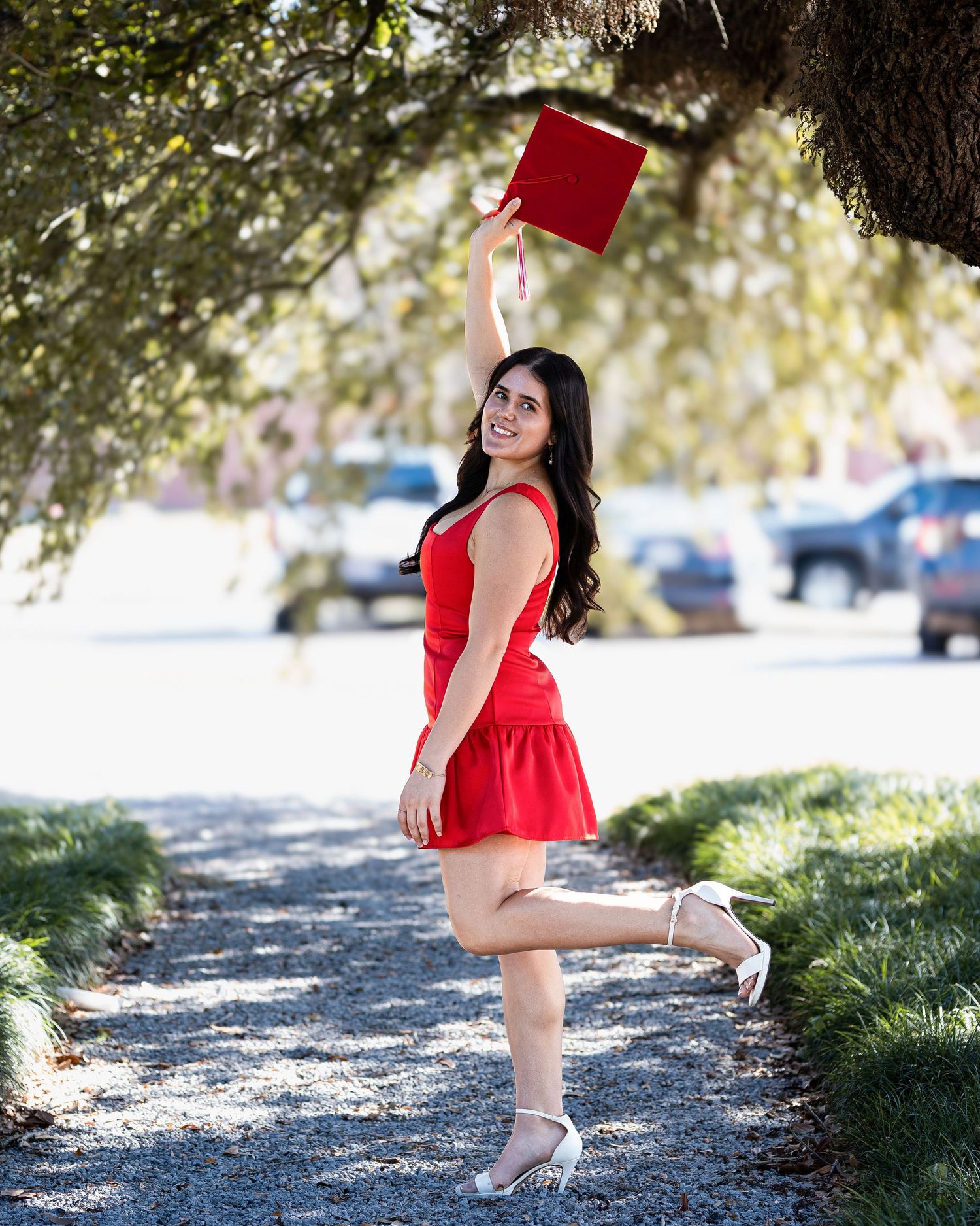 A sequence of photos showing a graduate in a red dress twirling and posing outdoors on a sunny day.