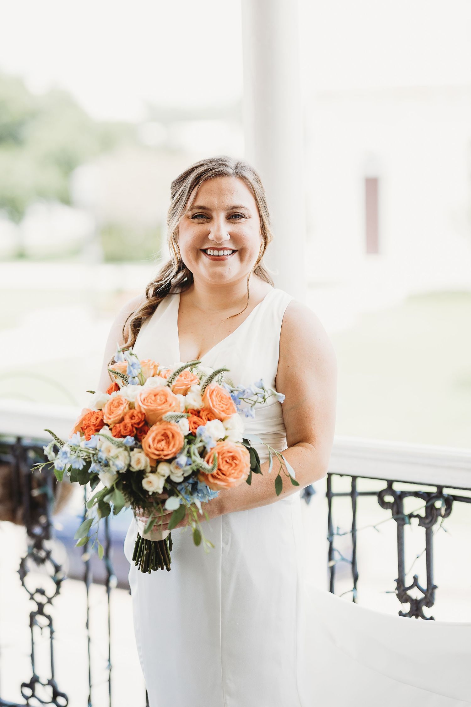 Beautiful bridal bouquet featuring peach roses and blue accents against white backdrop.