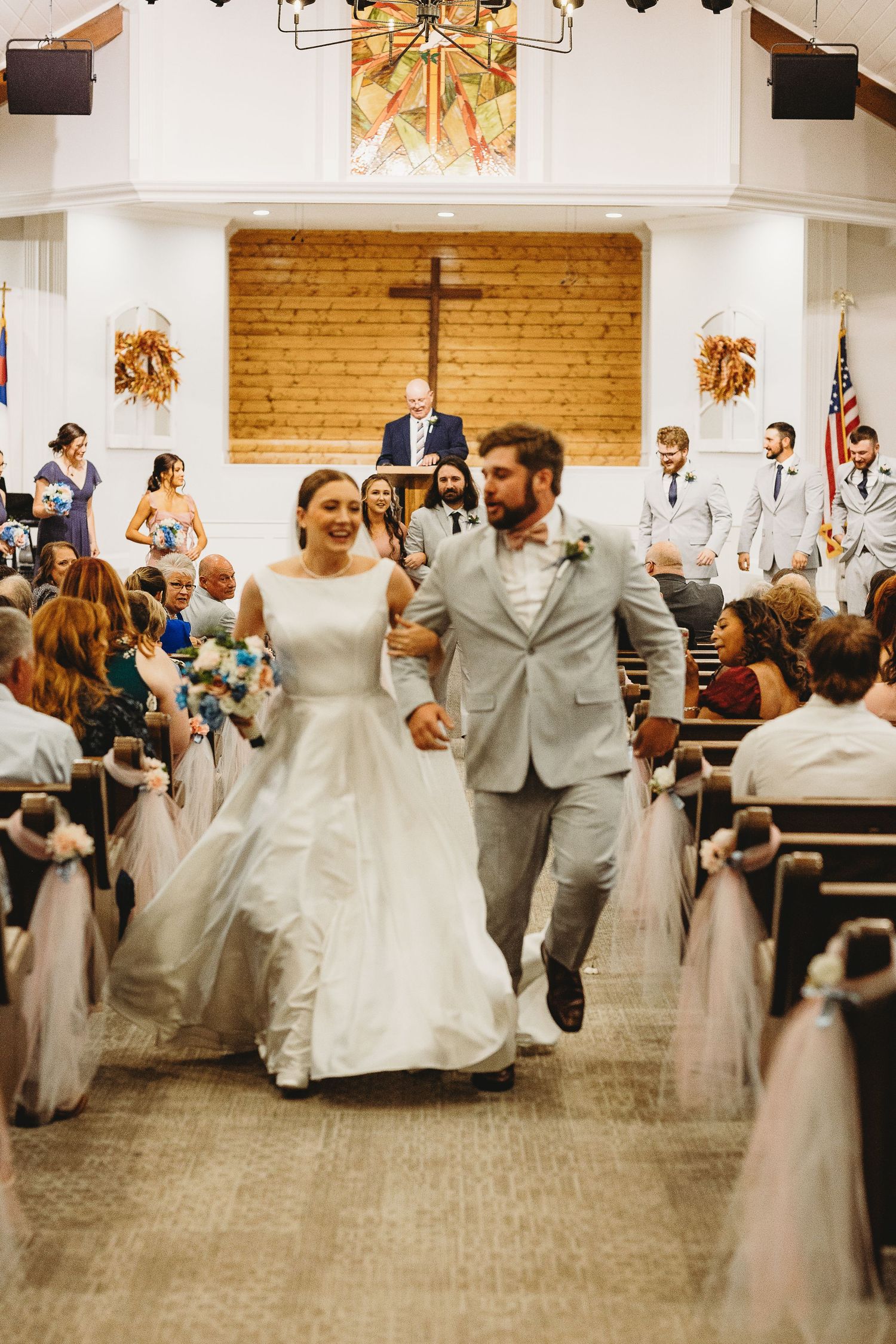 Wedding party celebrates with joyful dance moves in church reception hall.