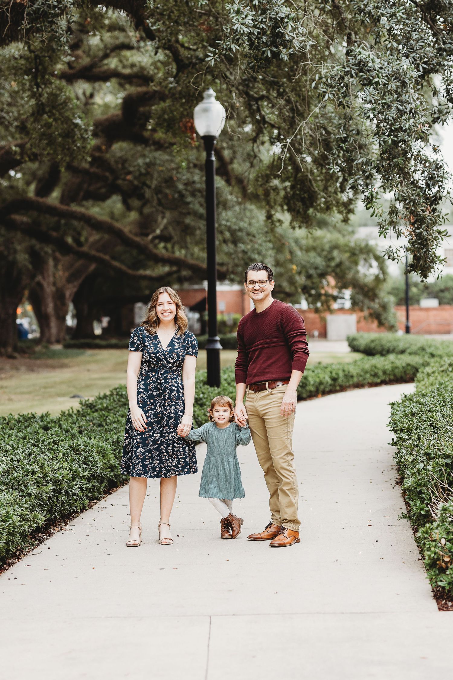 Family walking together on a tree-lined pathway during a lifestyle photo session.